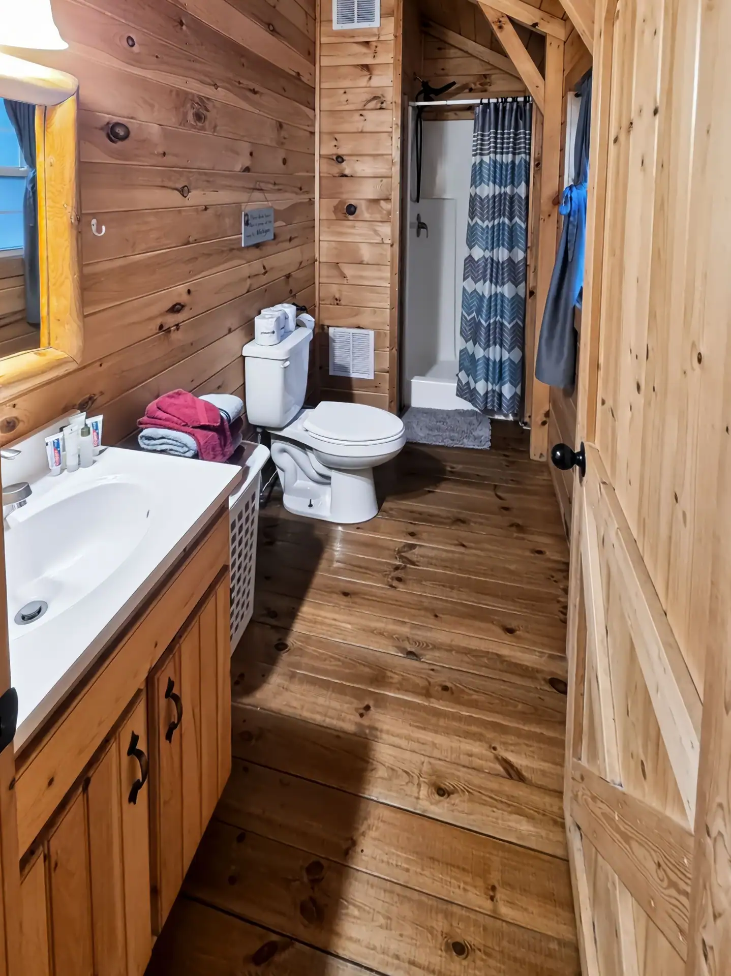 Pine-paneled bathroom with vanity, toilet, and walk-in shower at Buckeye Hut cabin