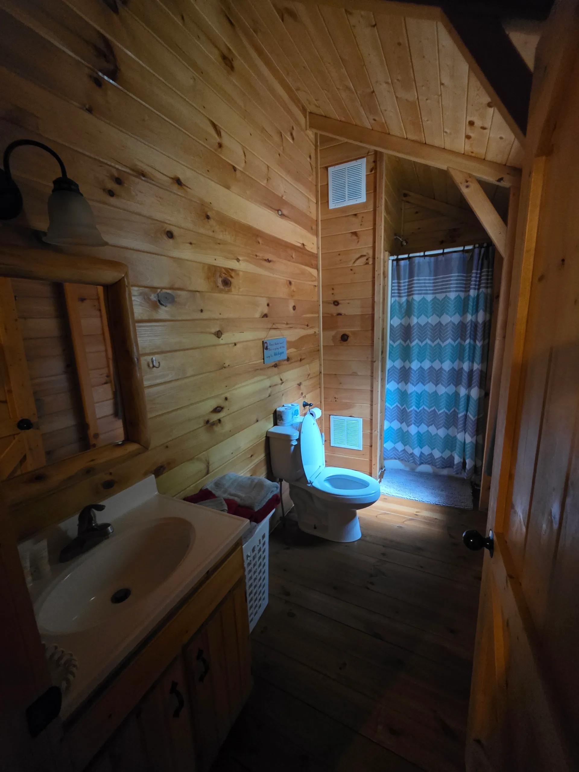 Pine-paneled bathroom with bathtub, vanity, and vaulted ceiling at Buckeye Hut cabin