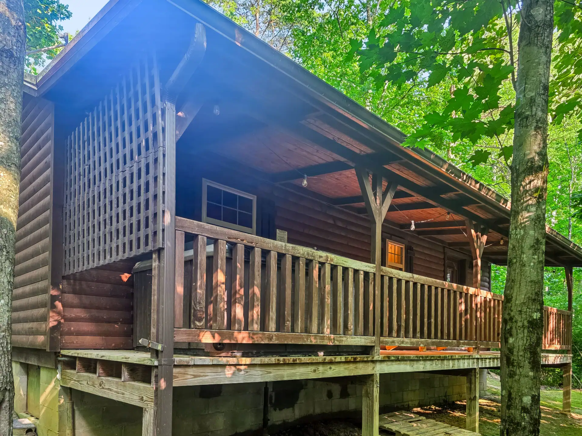 Covered porch with wooden railing and privacy lattice at Buckeye Hut cabin