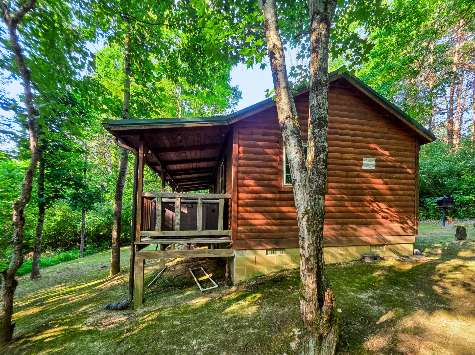 Covered porch at Buckeye Hut cabin seen from the wooded yard below