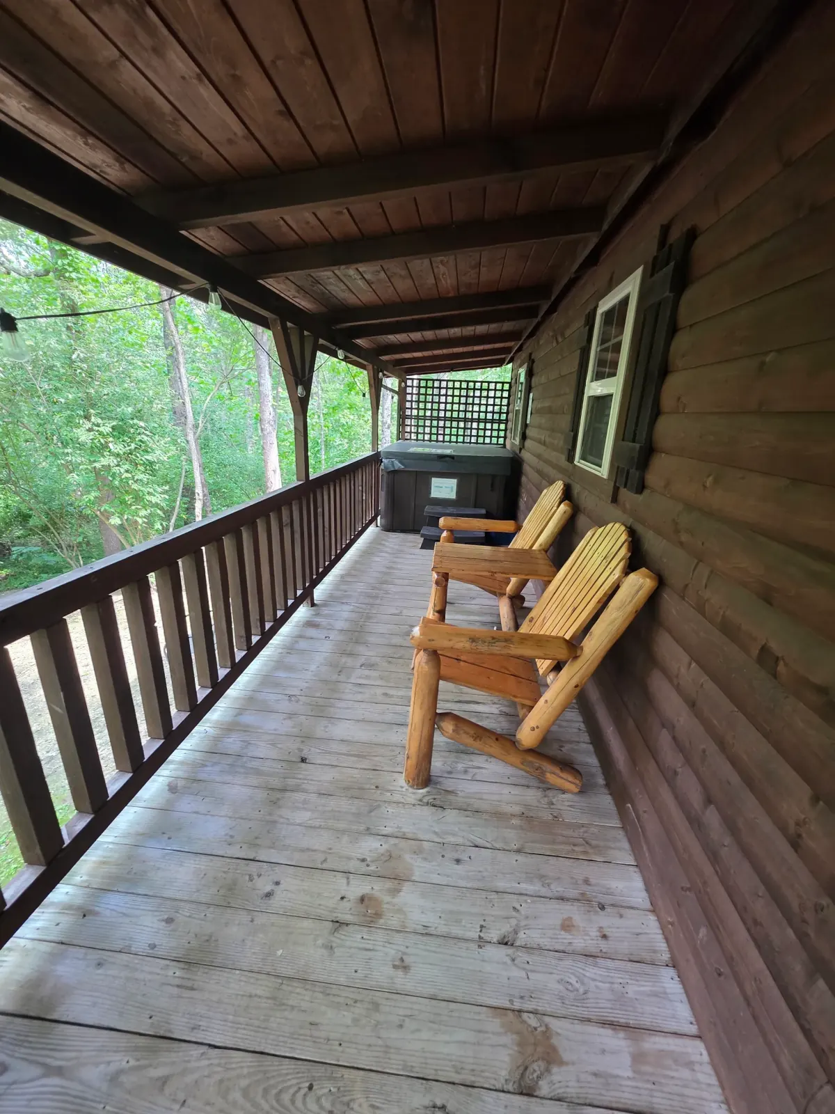 Covered wooden deck with log furniture and railing overlooking the forest at Buckeye Hut cabin