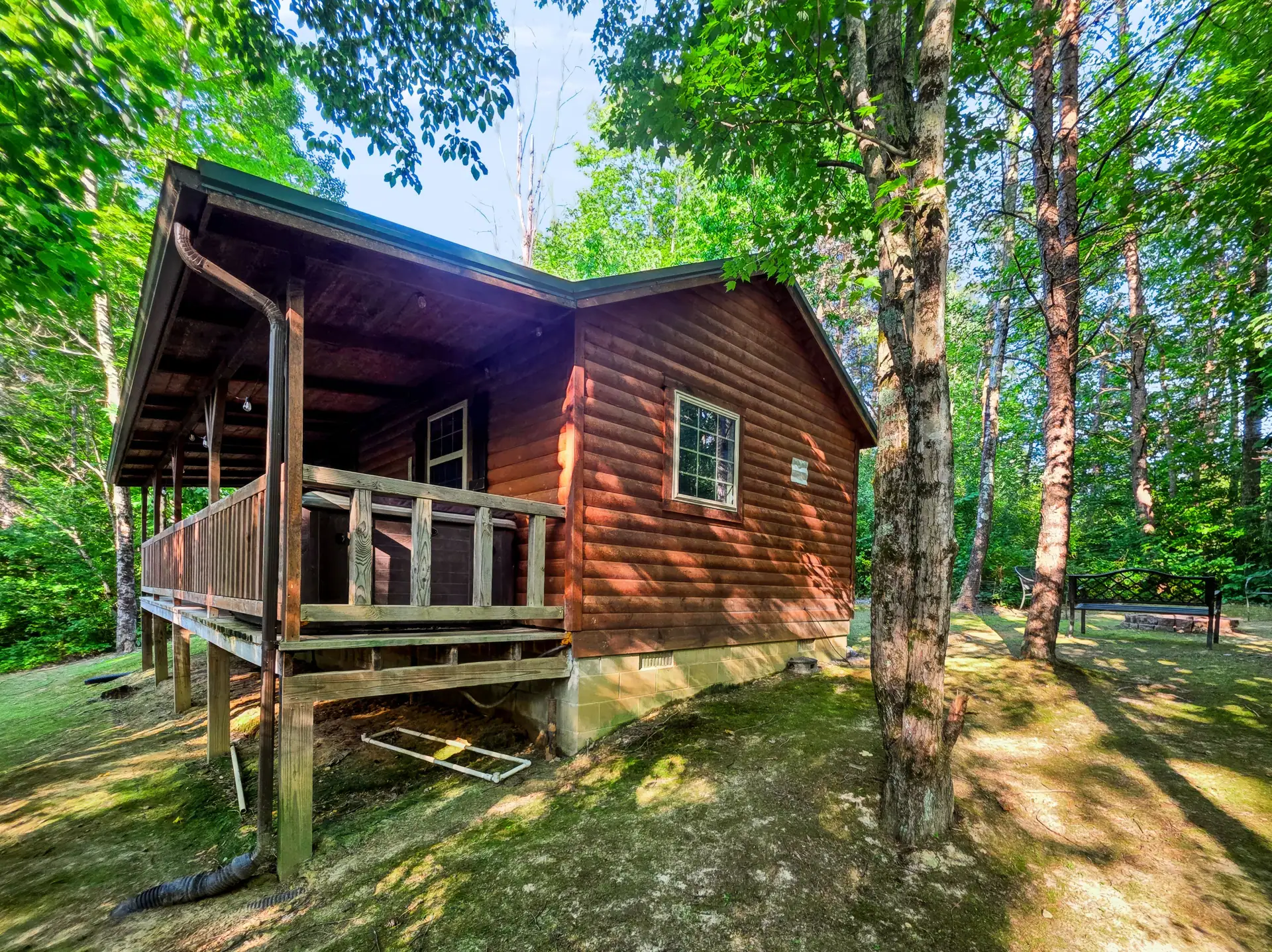 Corner of the covered porch at Buckeye Hut cabin framed by tall trees