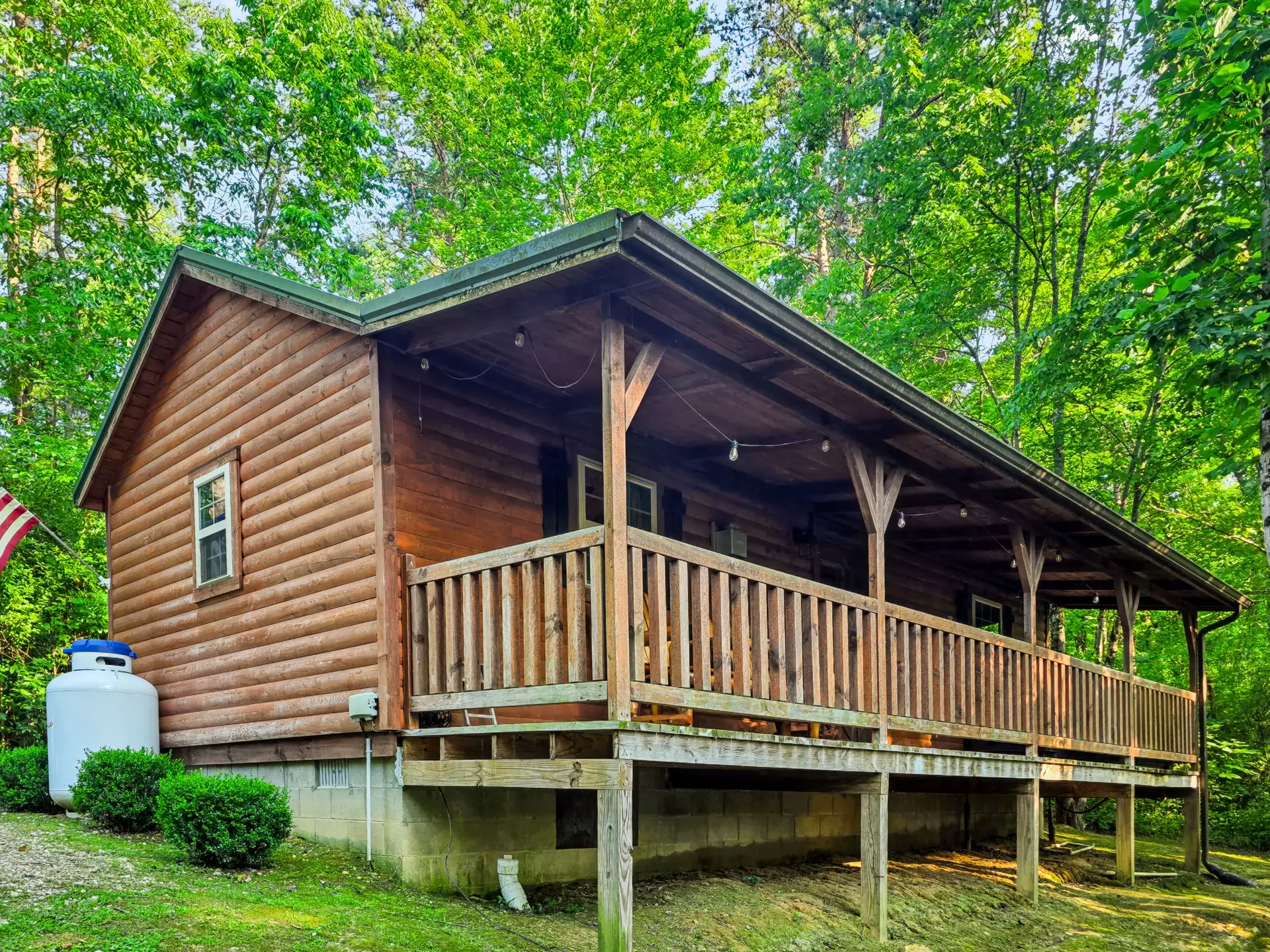 Buckeye Hut cabin with covered porch and wooden railing surrounded by forest