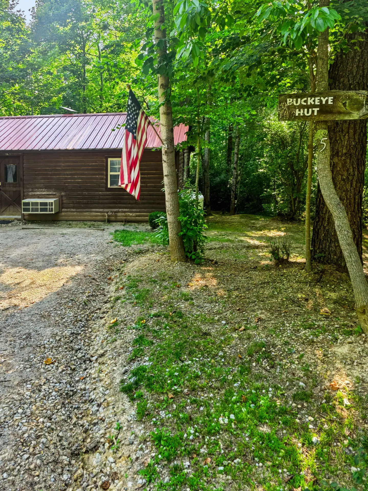 Buckeye Hut sign on a tree beside the gravel driveway leading to the cabin