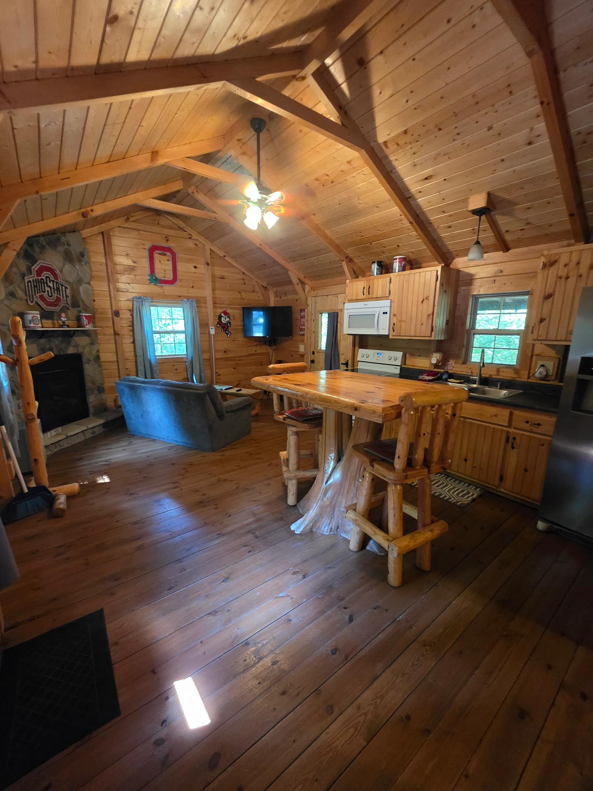 Full cabin overview from loft showing living room, kitchen, stone fireplace, and log furniture at Buckeye Hut cabin