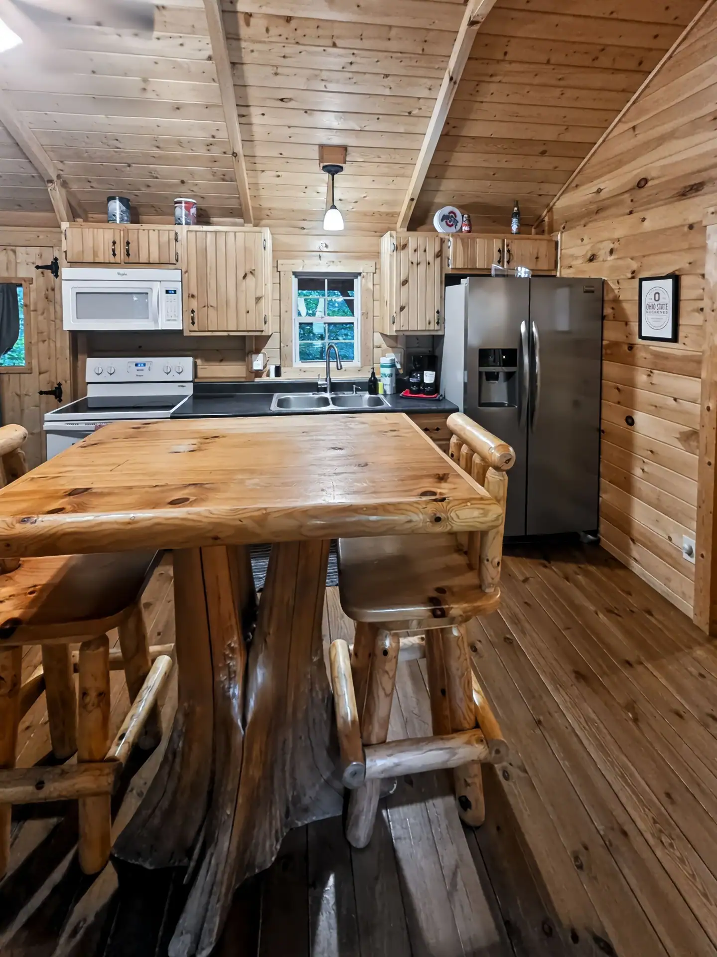 Log dining table with bar stools in front of the full kitchen at Buckeye Hut cabin