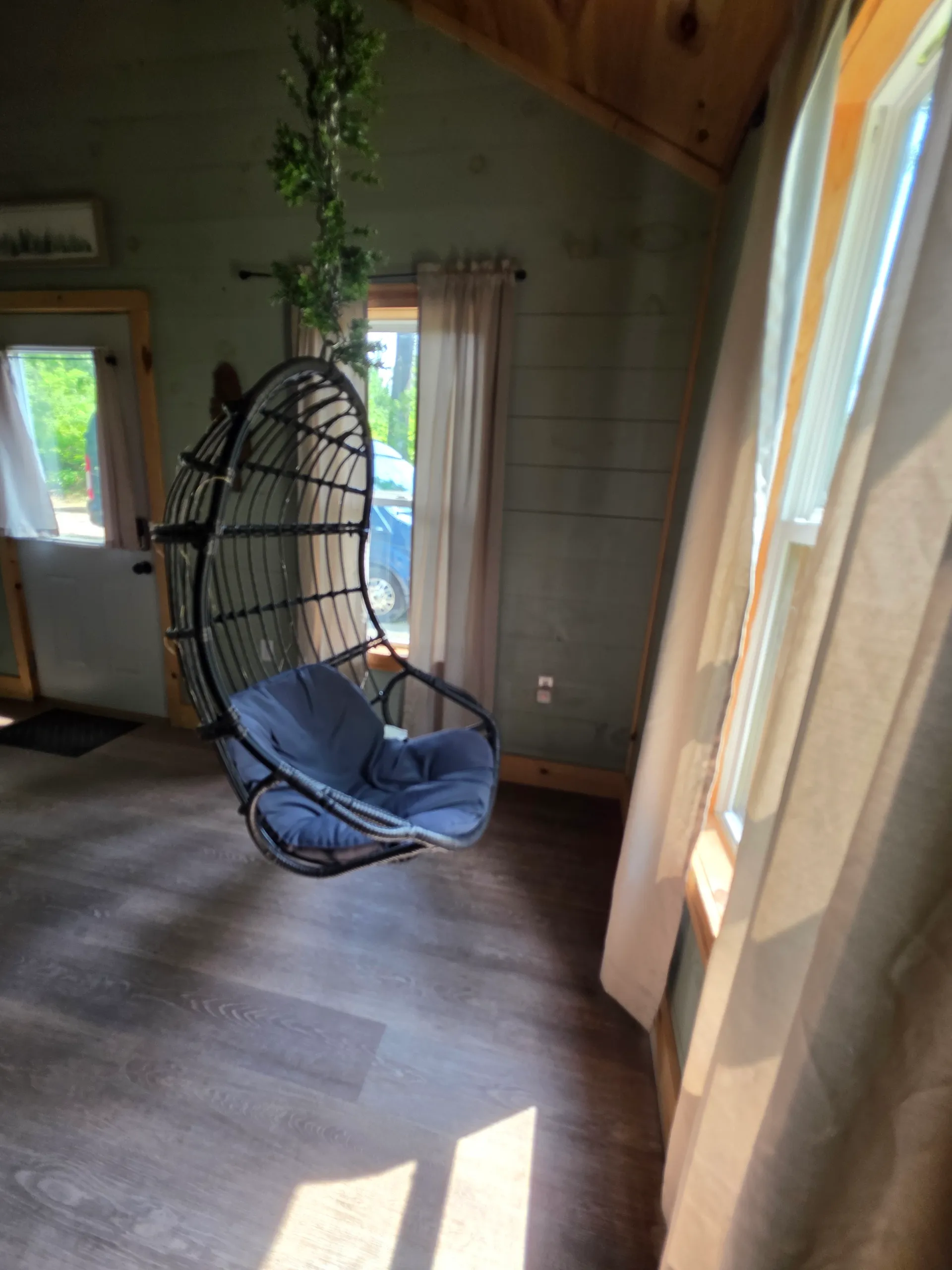 Covered front porch with black rocking chair and ceiling fan overlooking the forest at Butterfly Ridge cabin
