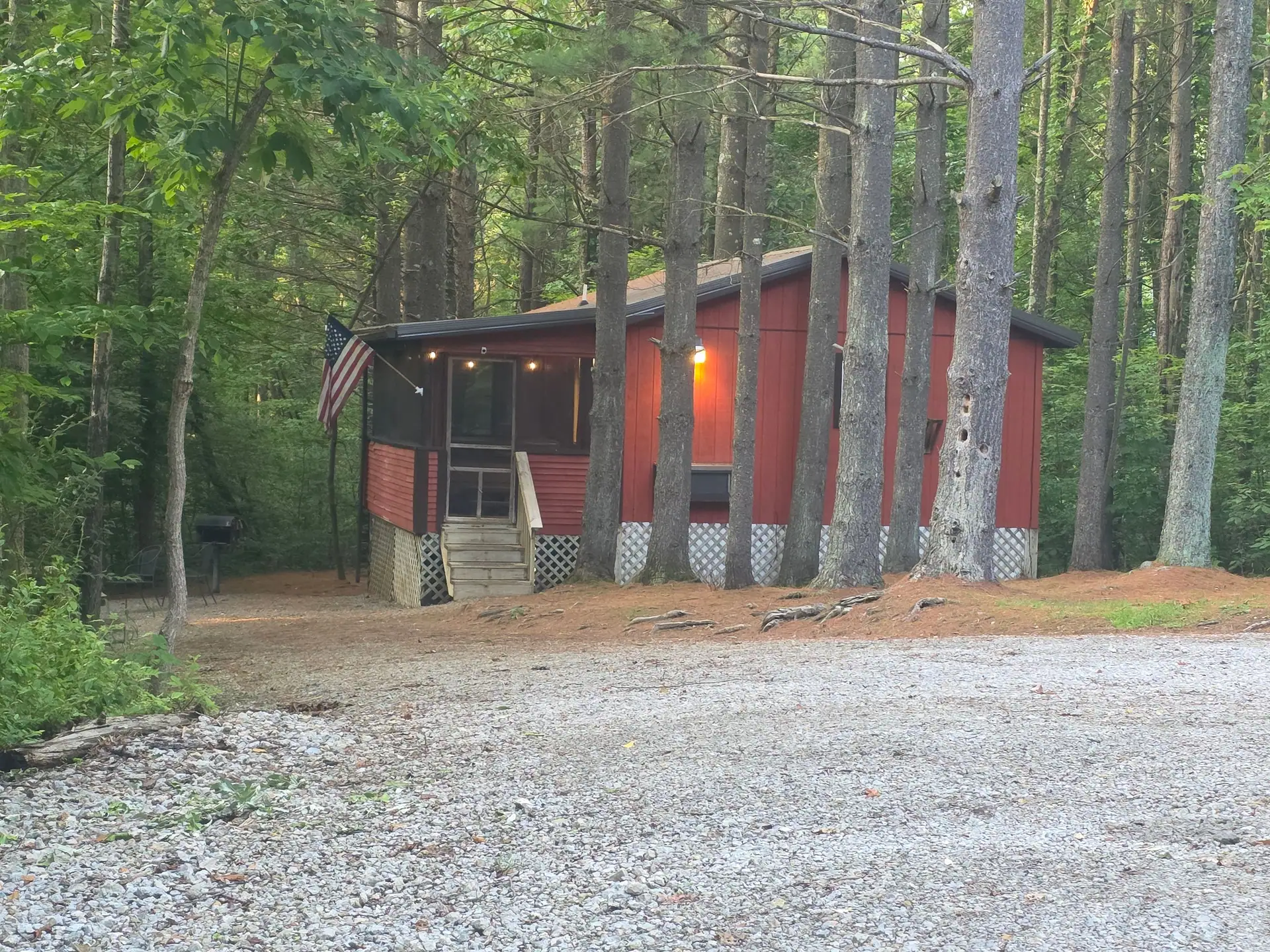 Cherokee Way cabin in the evening with porch lights on and a gravel parking area
