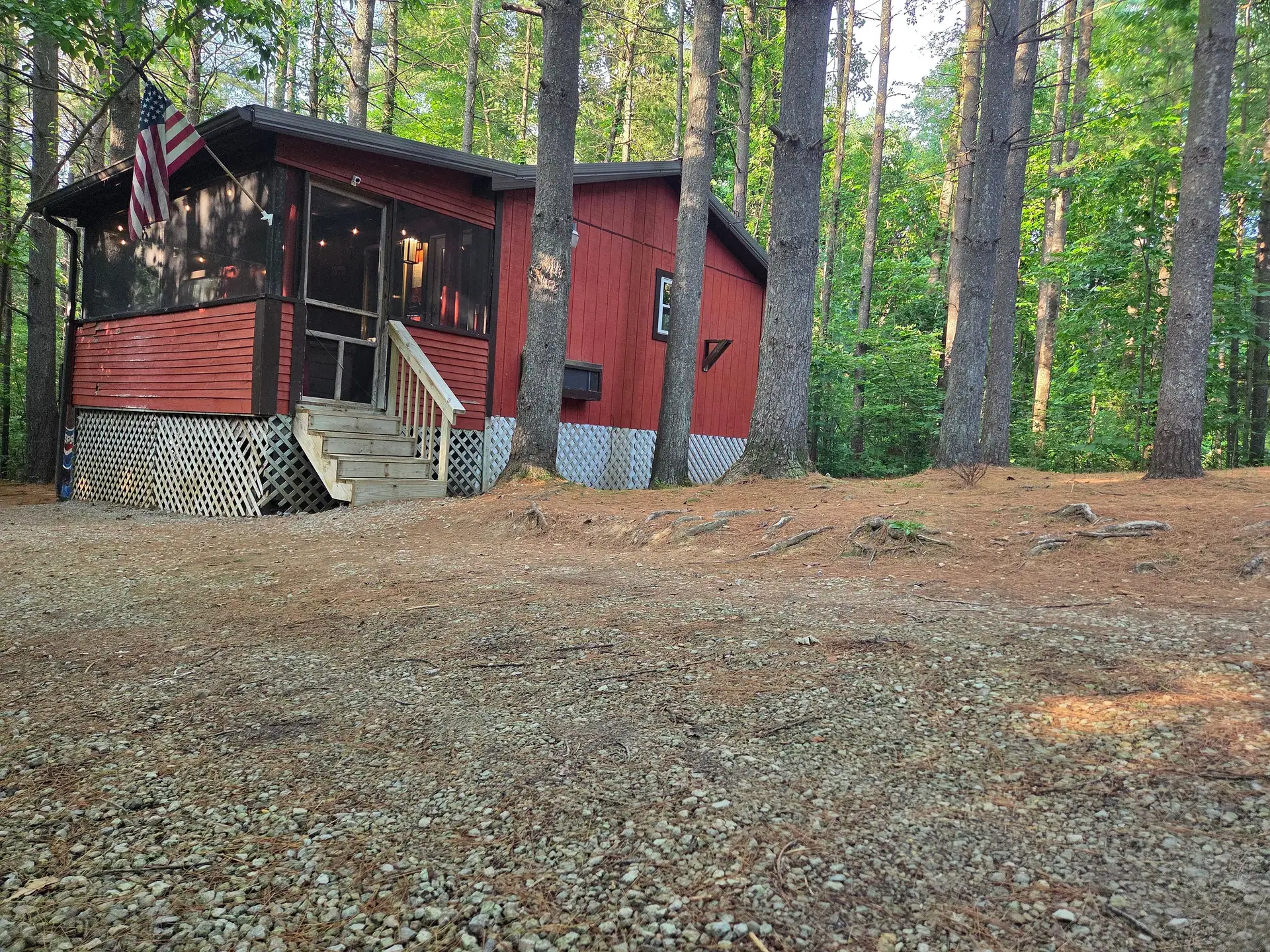 Cherokee Way cabin with red siding and a screened porch among tall pines in Hocking Hills