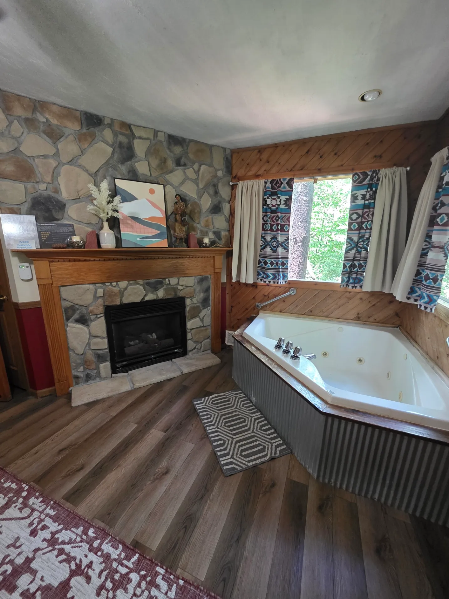 Overview of stone fireplace and corner jacuzzi room with patterned curtains at Cherokee Way cabin