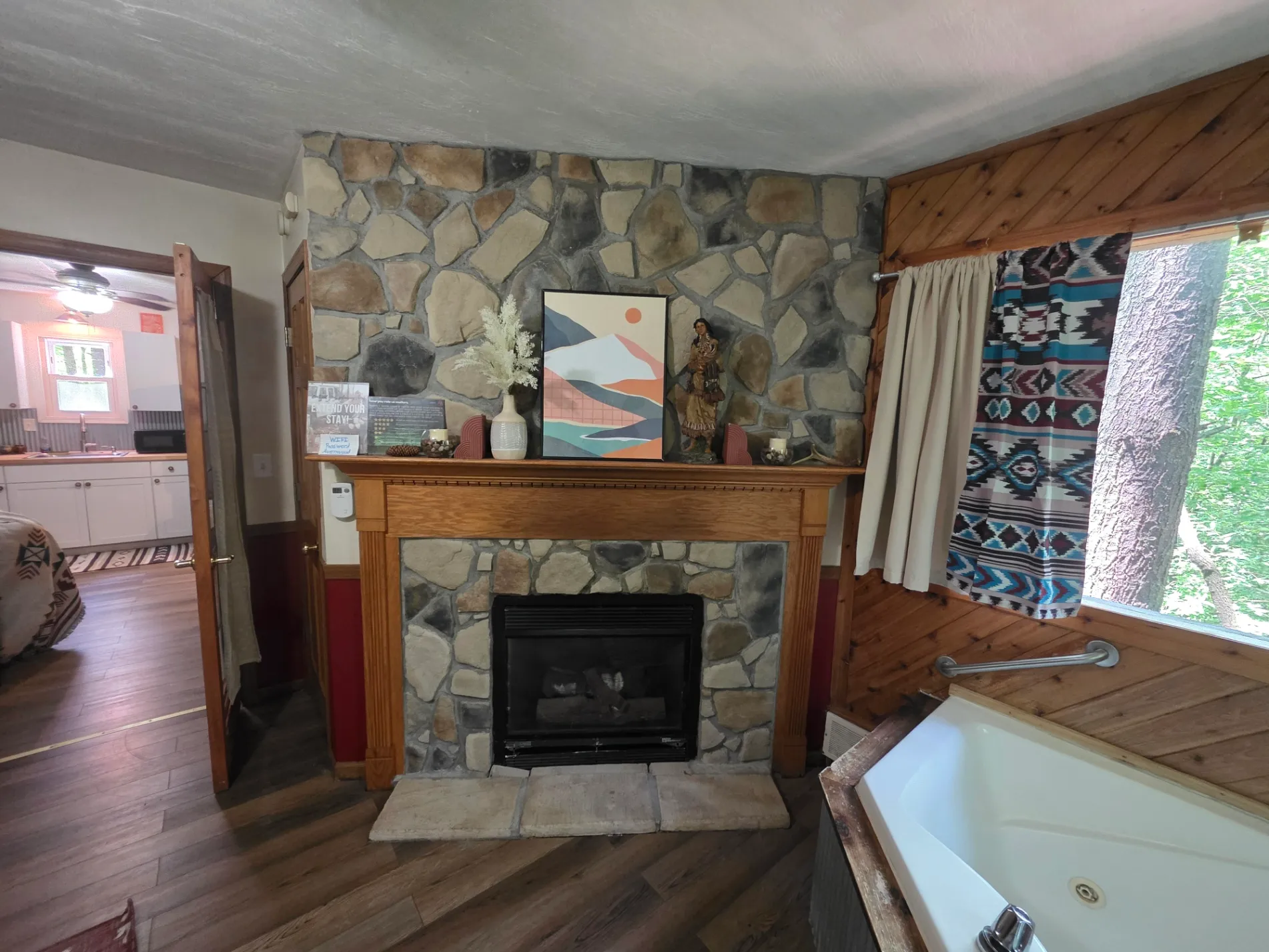 Stone fireplace with decorated mantel next to corner jacuzzi tub at Cherokee Way cabin