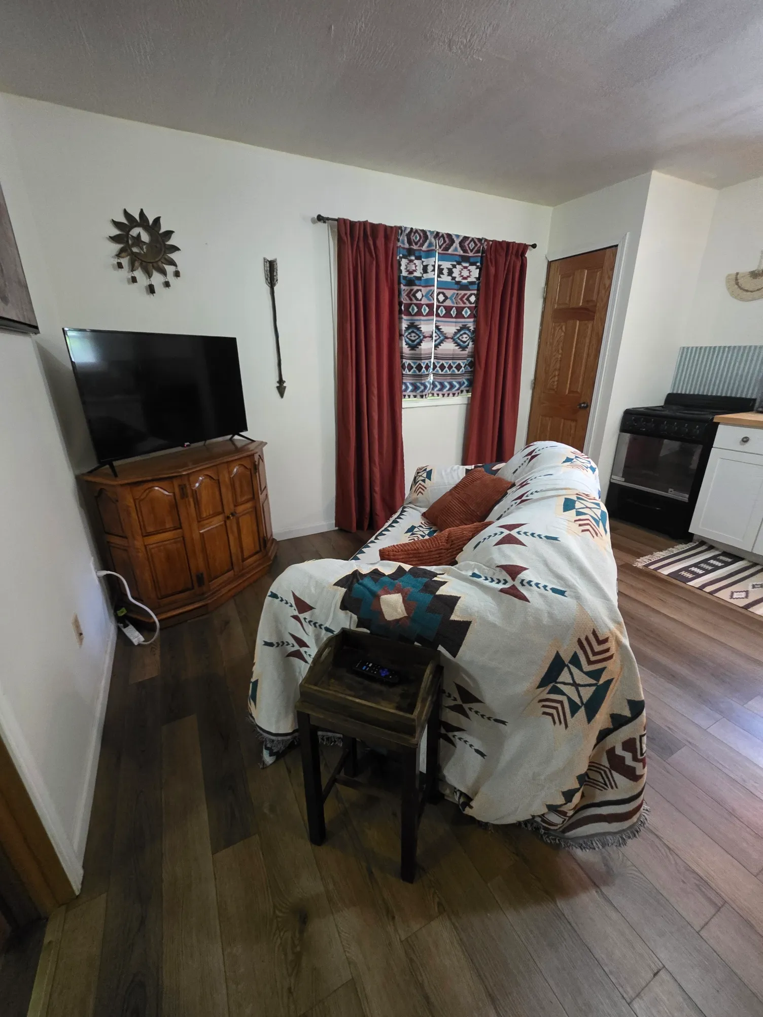 Living room with Southwestern themed blanket on sofa, rocking chair, and TV at Cherokee Way cabin
