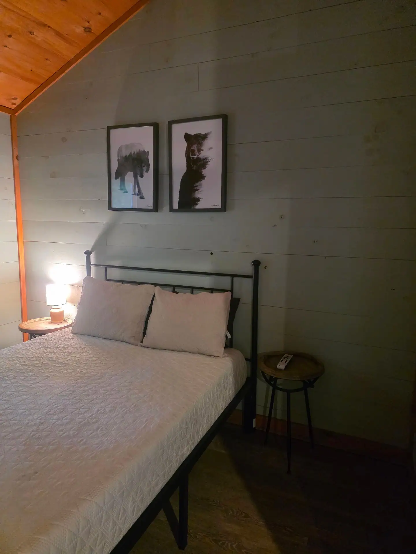 Queen bed with iron frame, bedside lamp and bear artwork at Dogwood Run cabin