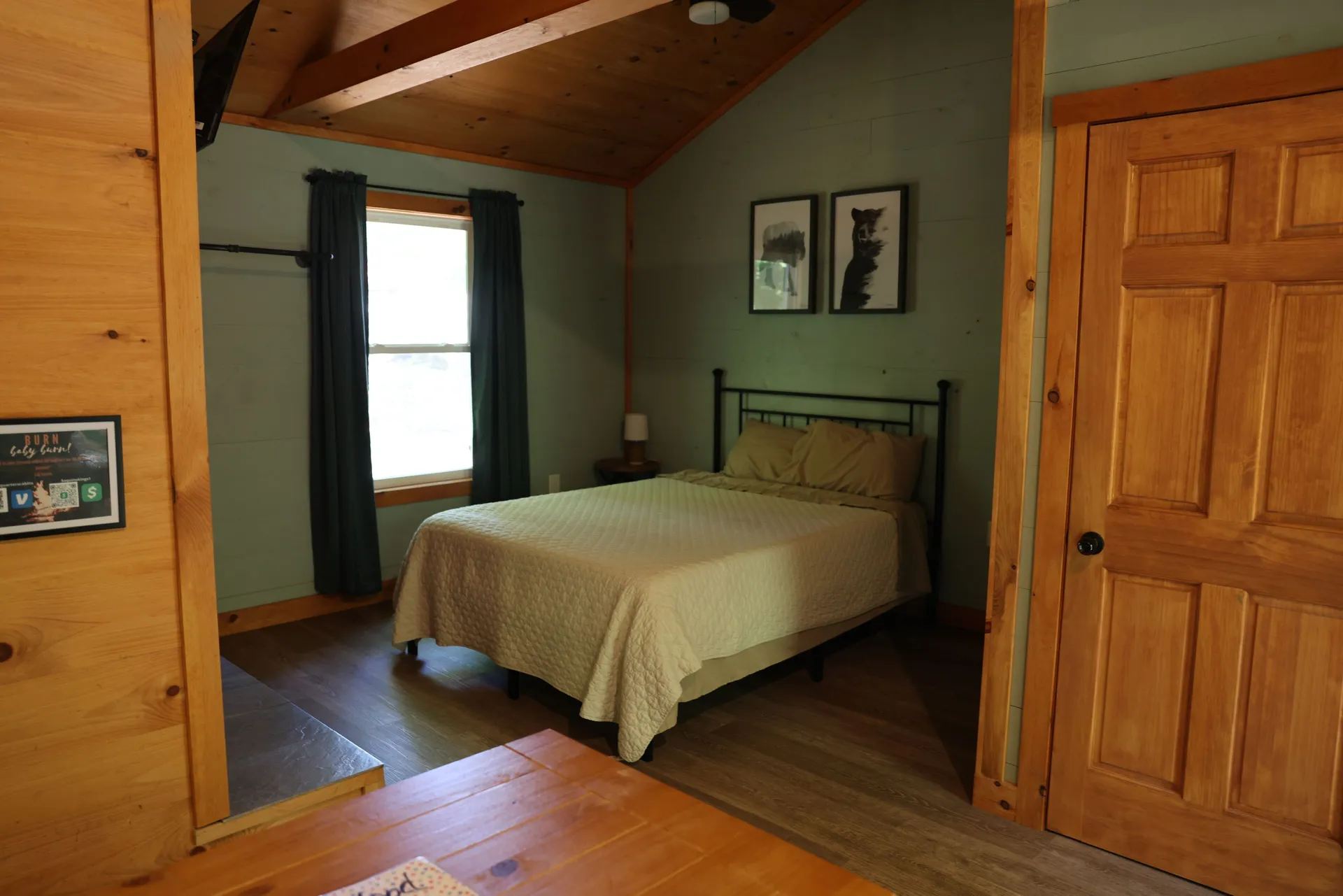 Bedroom with queen bed, iron frame, green accent wall, and bear artwork at Dogwood Run cabin