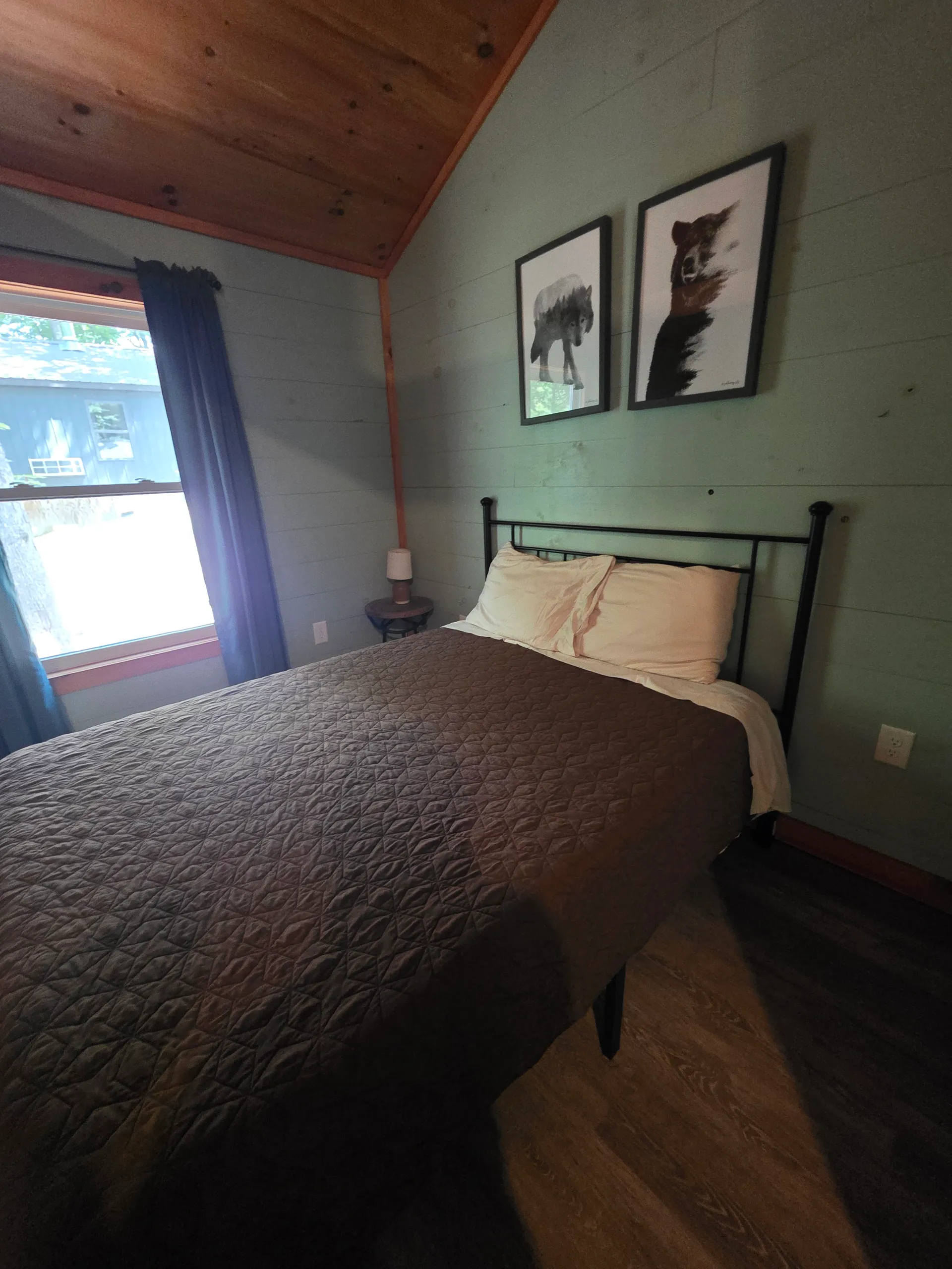 Queen bed close-up with tan quilt and nature artwork above at Dogwood Run cabin
