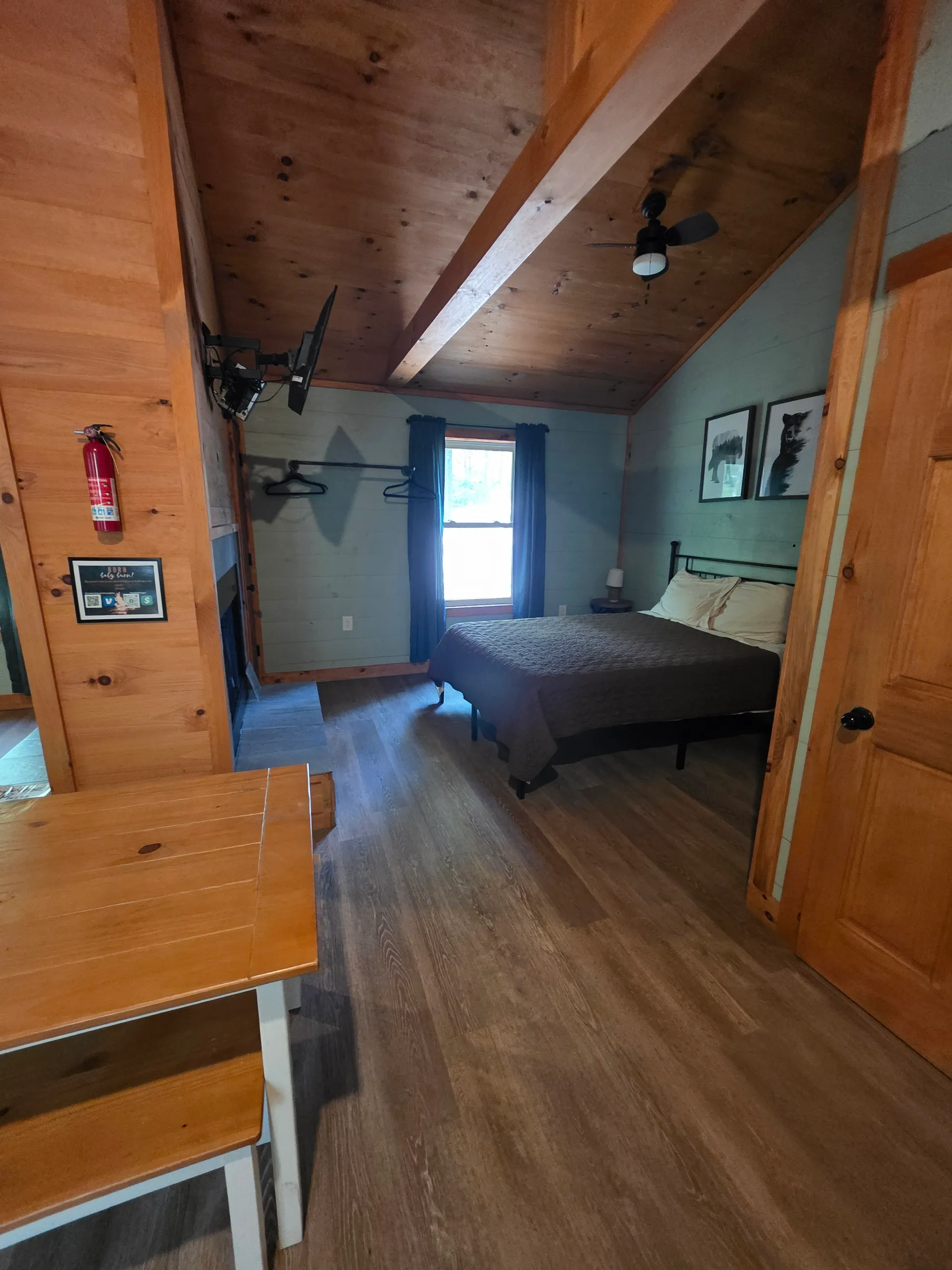 Bedroom with view of the wood-paneled fireplace wall and loft shelf at Dogwood Run cabin