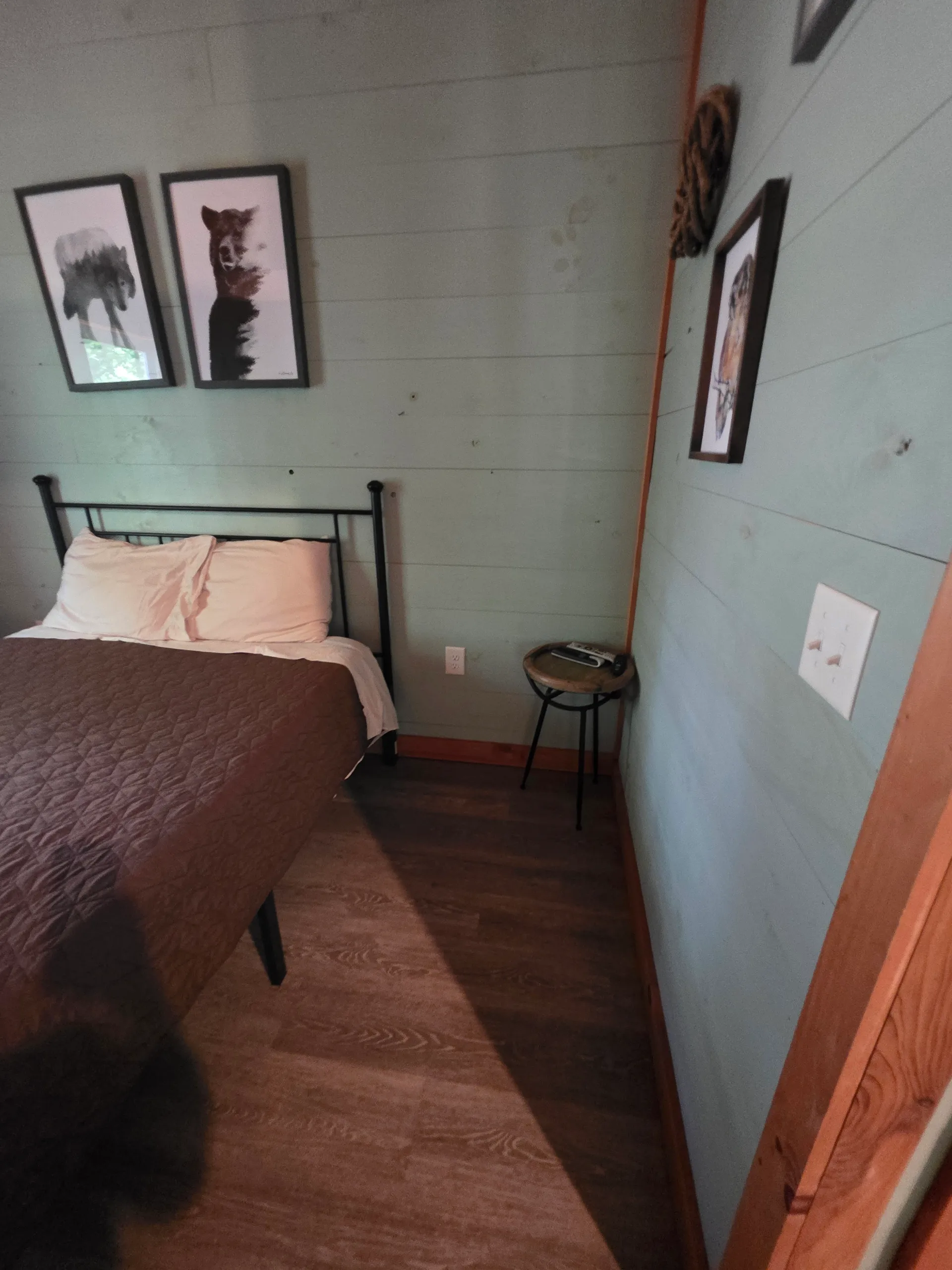 Bedroom with queen bed, bear prints on the green wall, and iron bed frame at Dogwood Run cabin