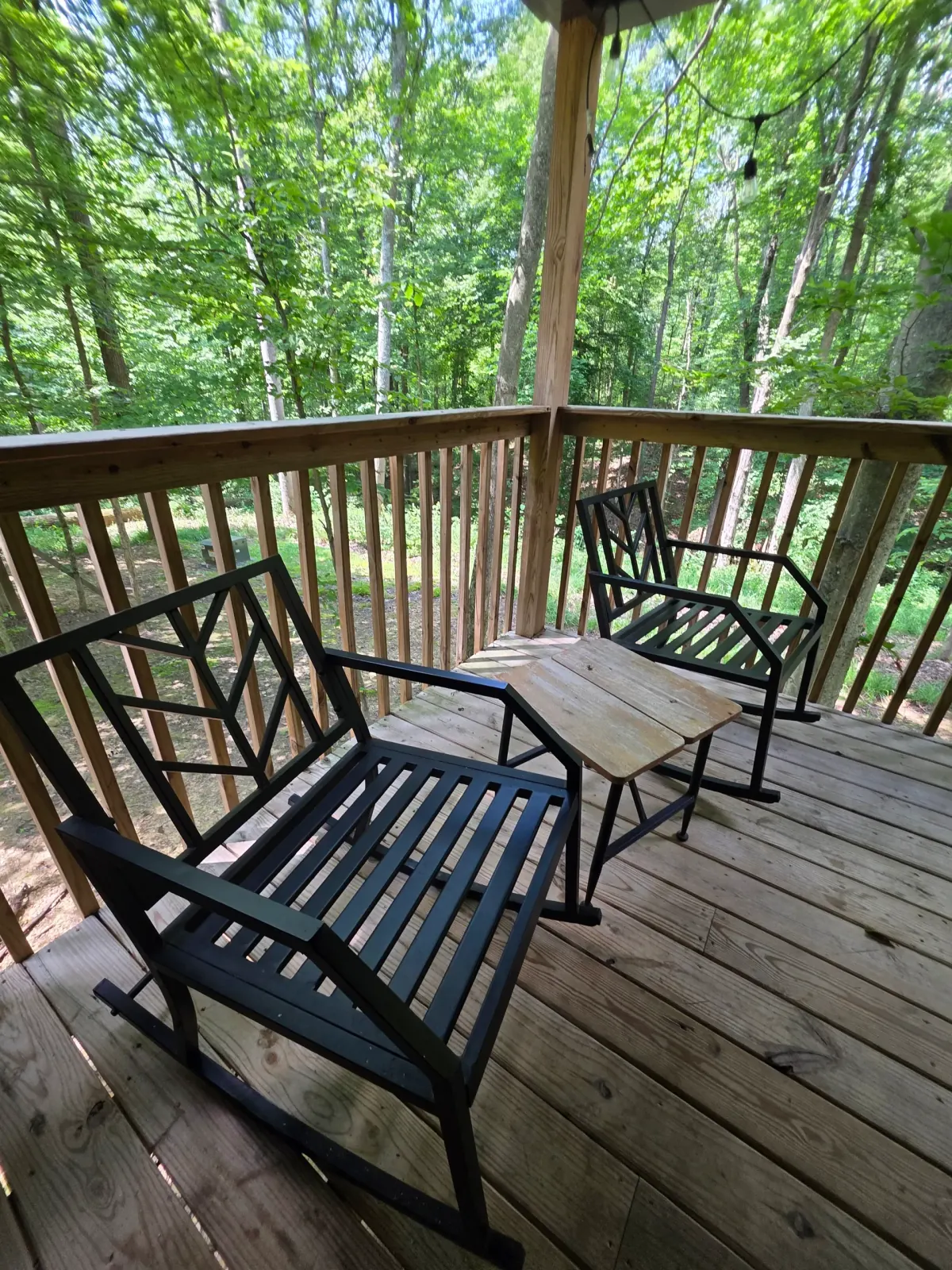 Metal patio chairs on the covered deck overlooking the green forest at Dogwood Run cabin