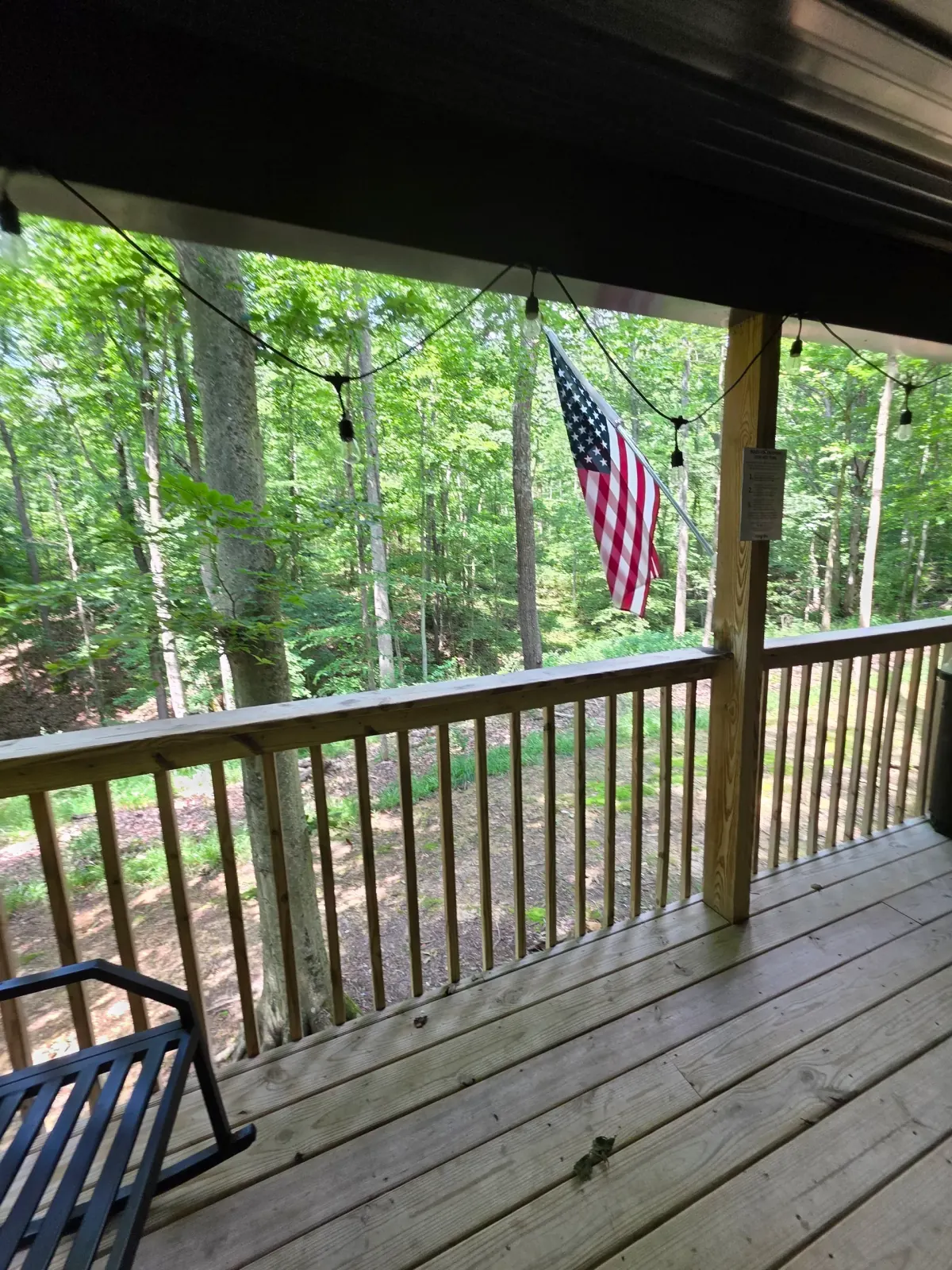Deck view with American flag and railing looking out into the woods at Dogwood Run cabin