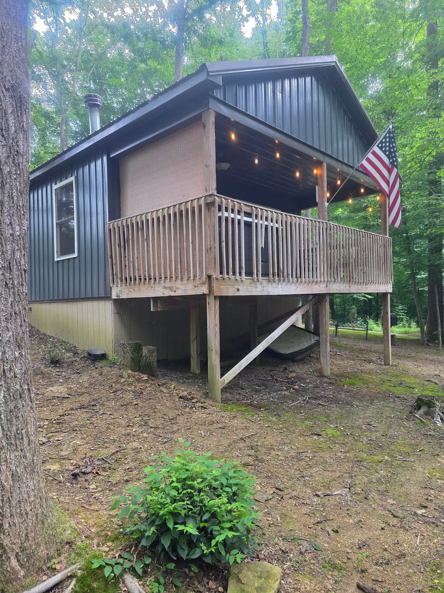 Back of Dogwood Run cabin with the raised covered deck, flag and string lights