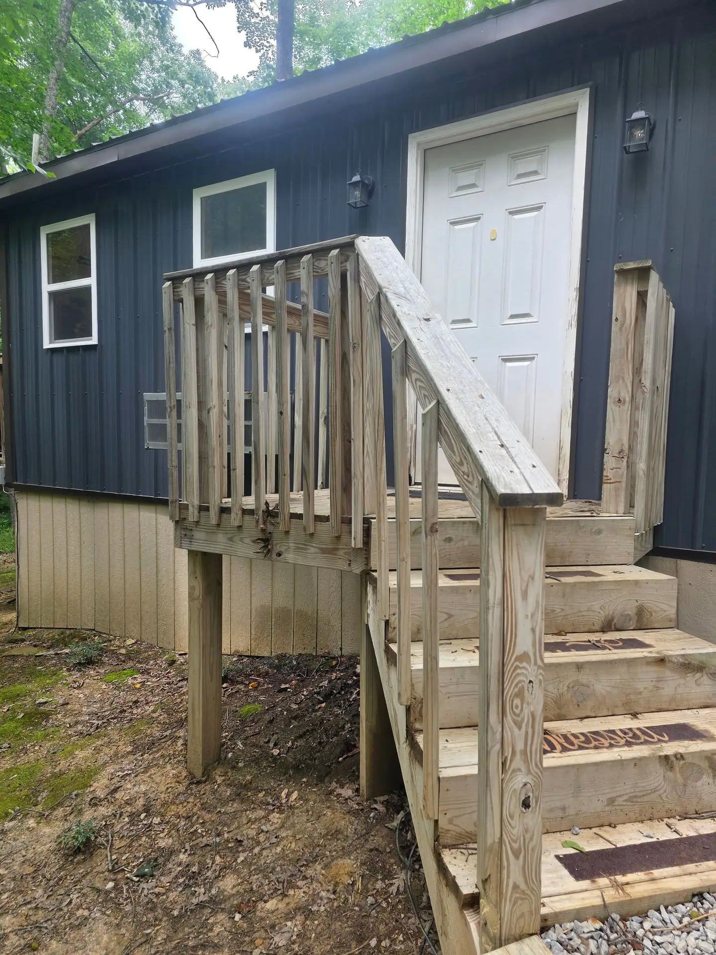 Wooden steps leading up to the white front door of Dogwood Run cabin