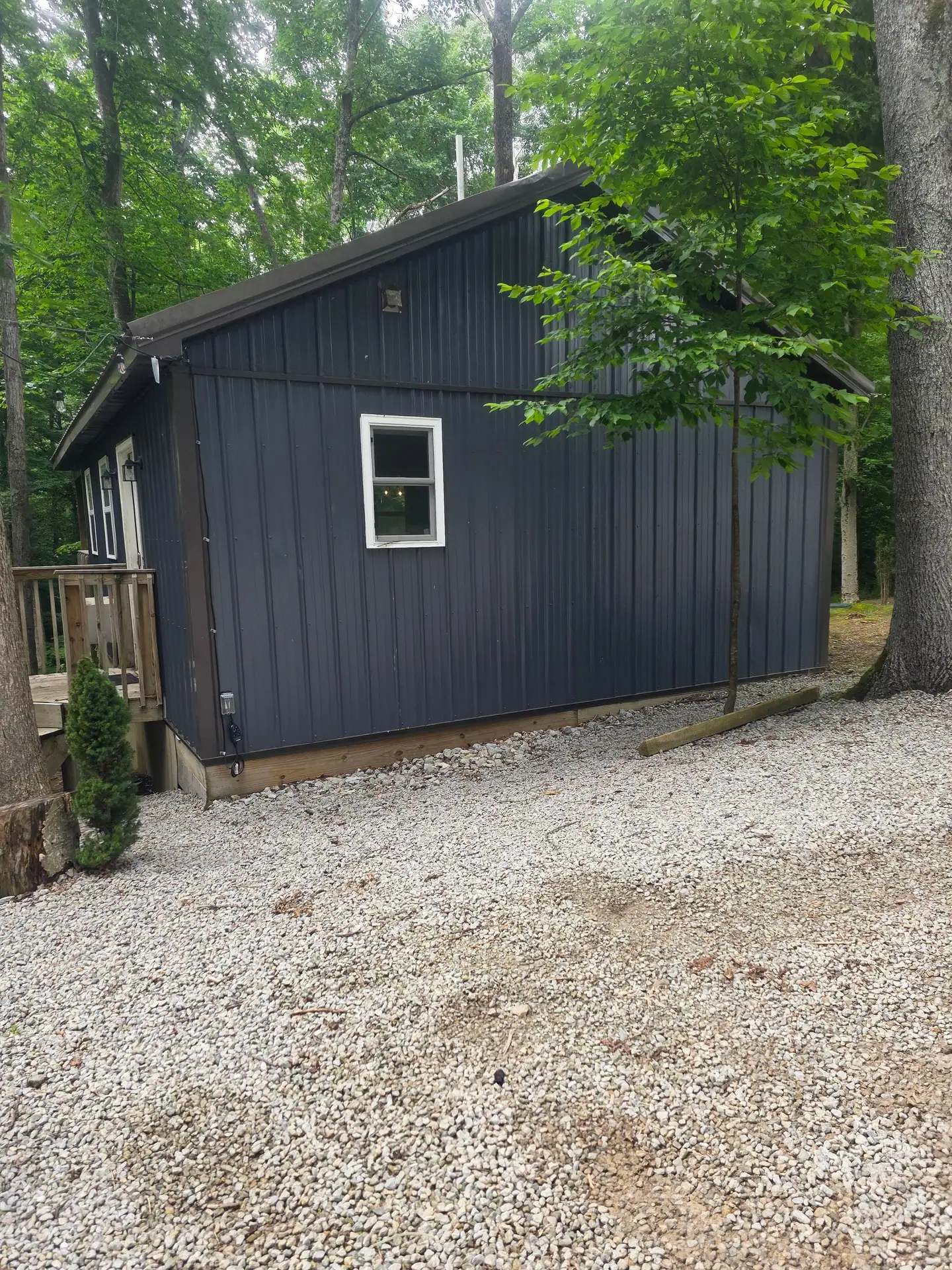 Side view of Dogwood Run cabin with navy siding and the gravel parking area