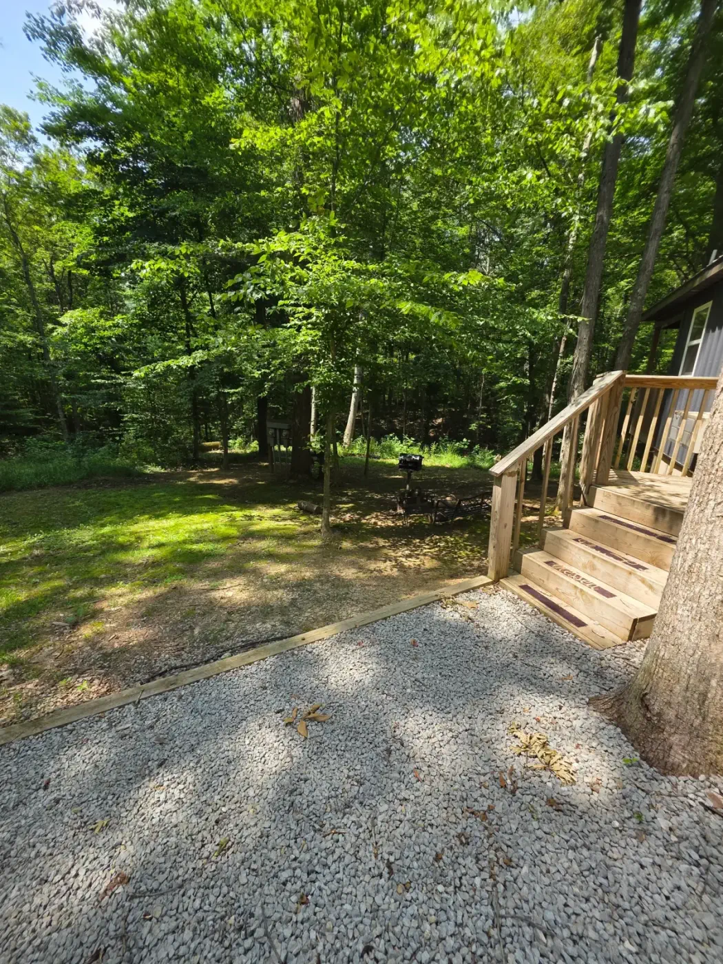 Wide yard view with cabin and wooden deck stairs at Dogwood Run