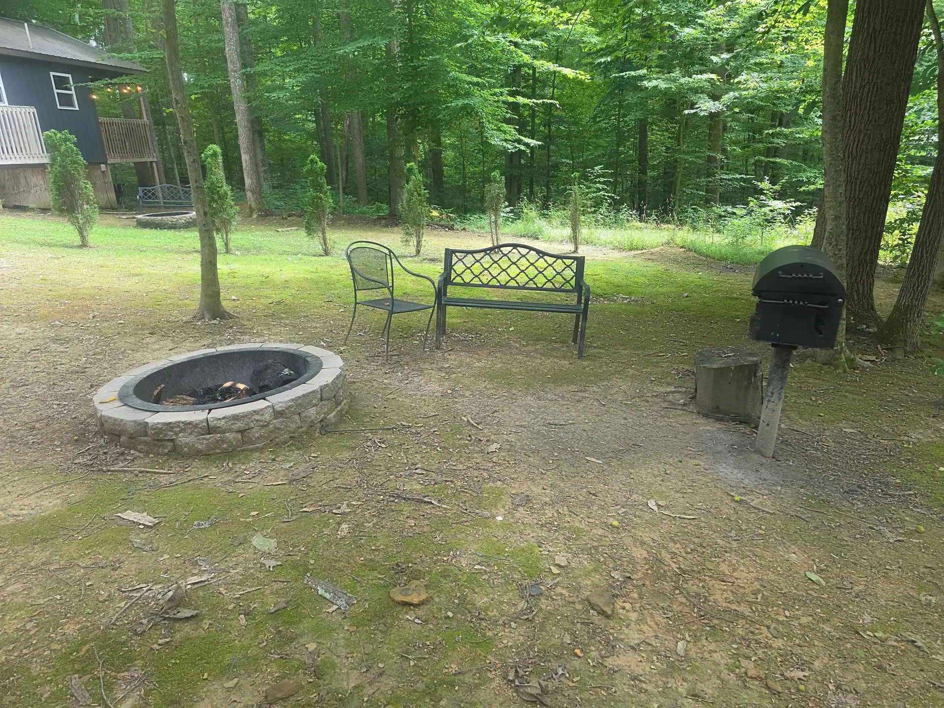 Fire pit with bench, metal chair and charcoal grill in the yard at Dogwood Run cabin