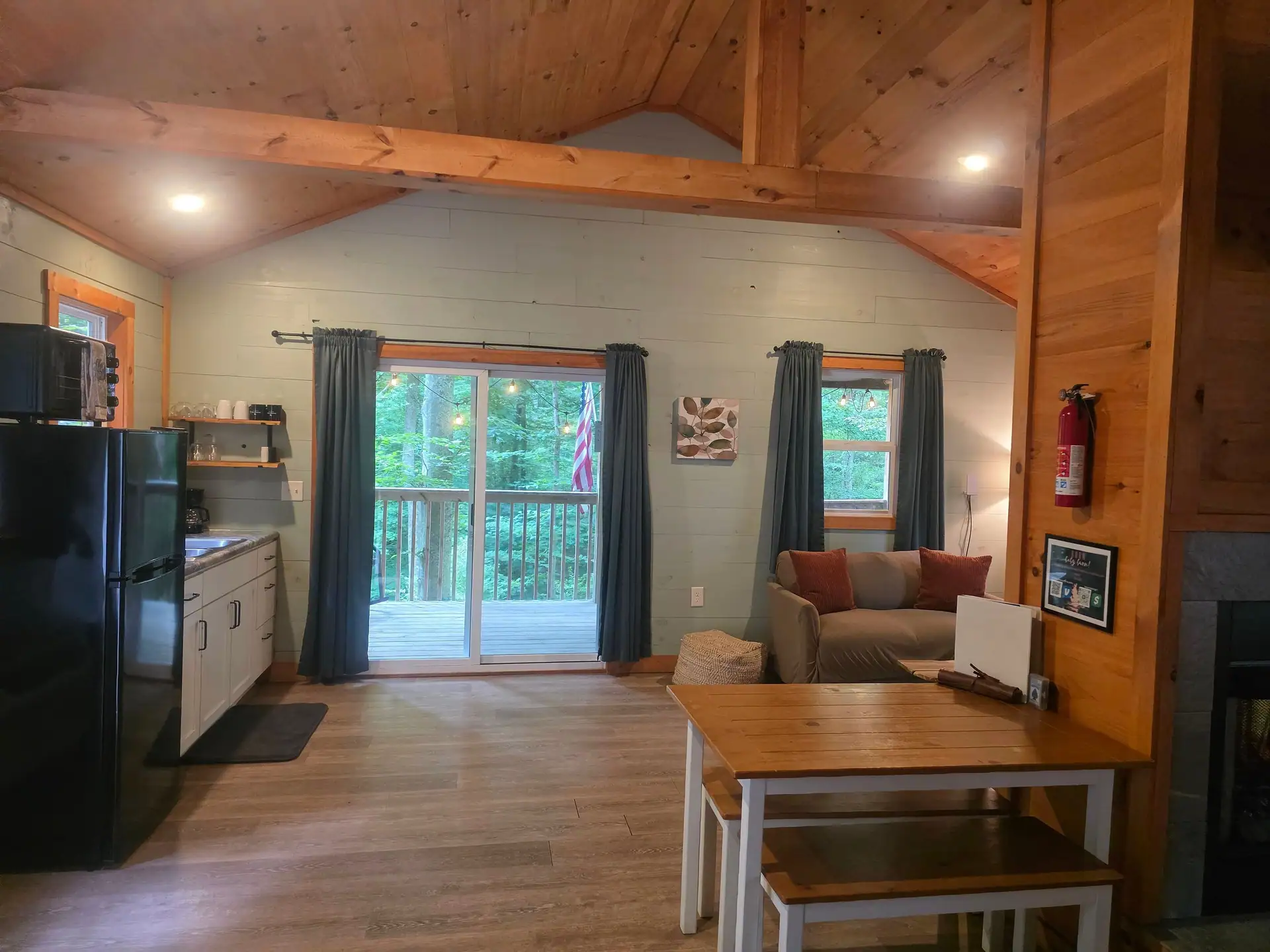 Open living space with kitchenette, sofa, dining table and sliding door to the deck at Dogwood Run cabin