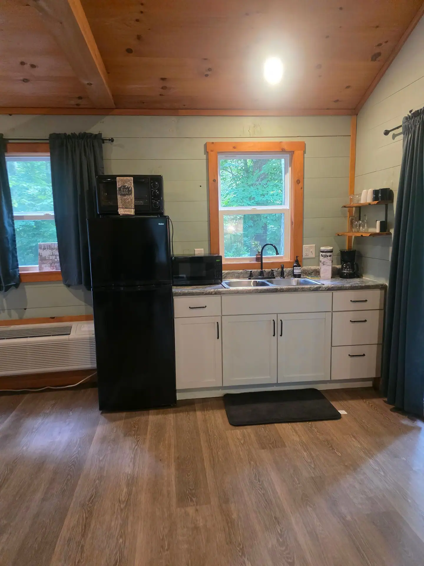 Kitchenette with white cabinets, black refrigerator and microwave at Dogwood Run cabin