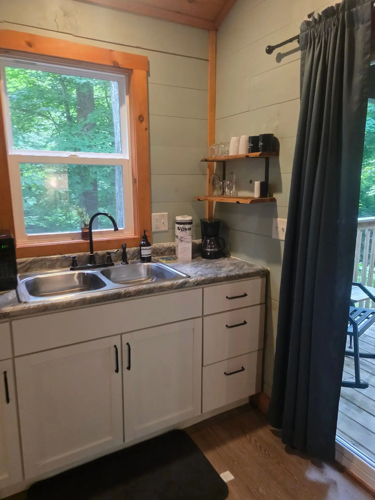 Kitchenette counter with double sink under a forest-view window at Dogwood Run cabin