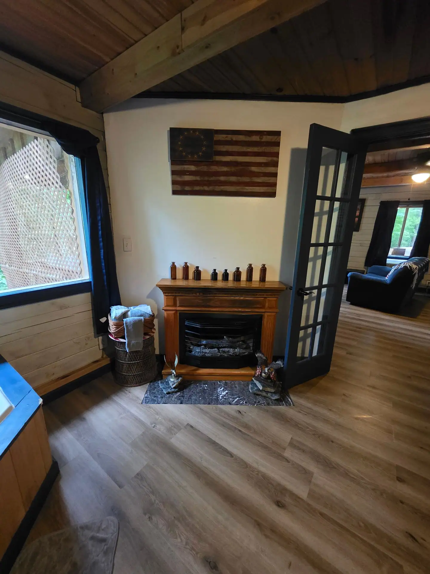 Wood-surround fireplace with eagle figures and French doors to the living room at Eagles Nest cabin