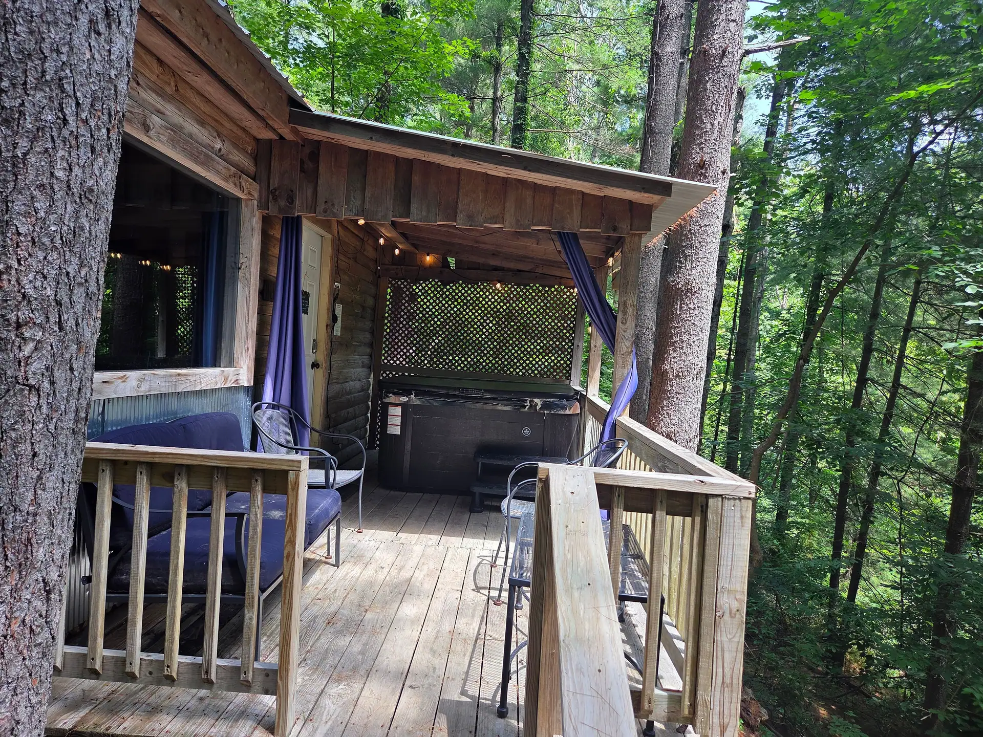 Covered back deck at Eagles Nest cabin with outdoor sofa, chairs and the hot tub