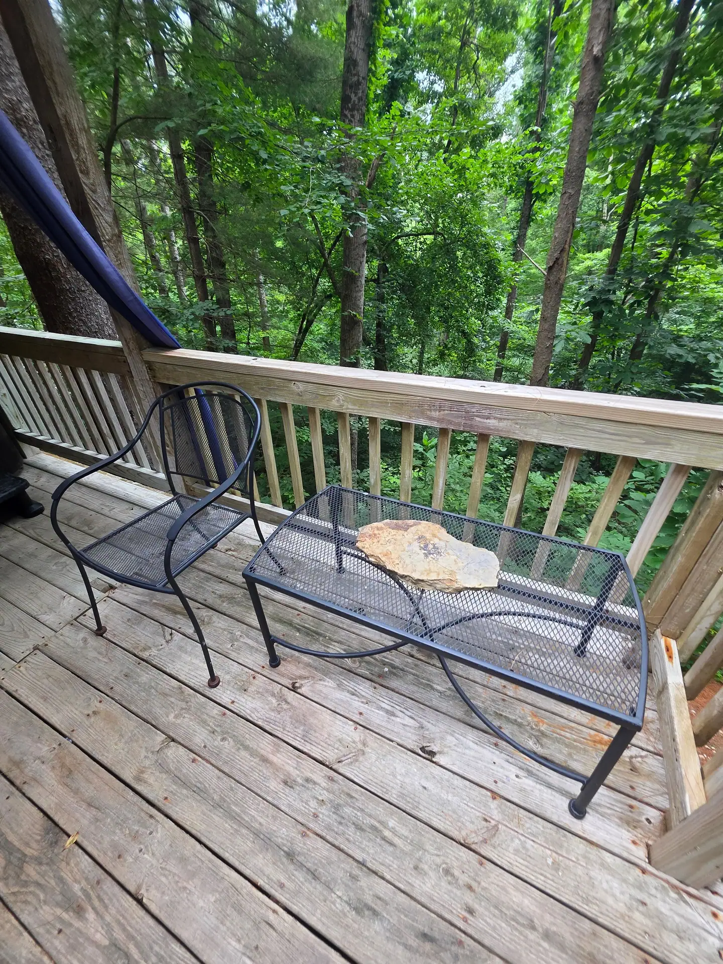 Metal bistro chair and table on the deck at Eagles Nest cabin overlooking the woods