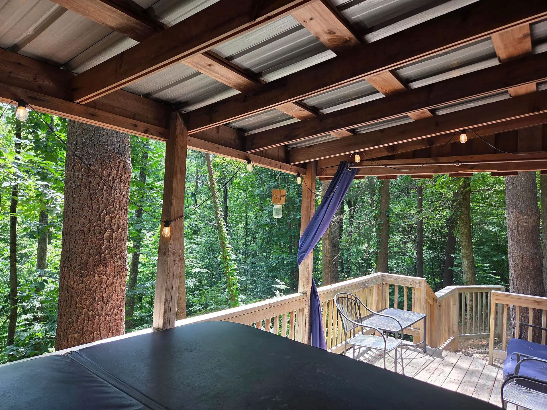 View from the covered deck at Eagles Nest cabin with string lights and forest beyond