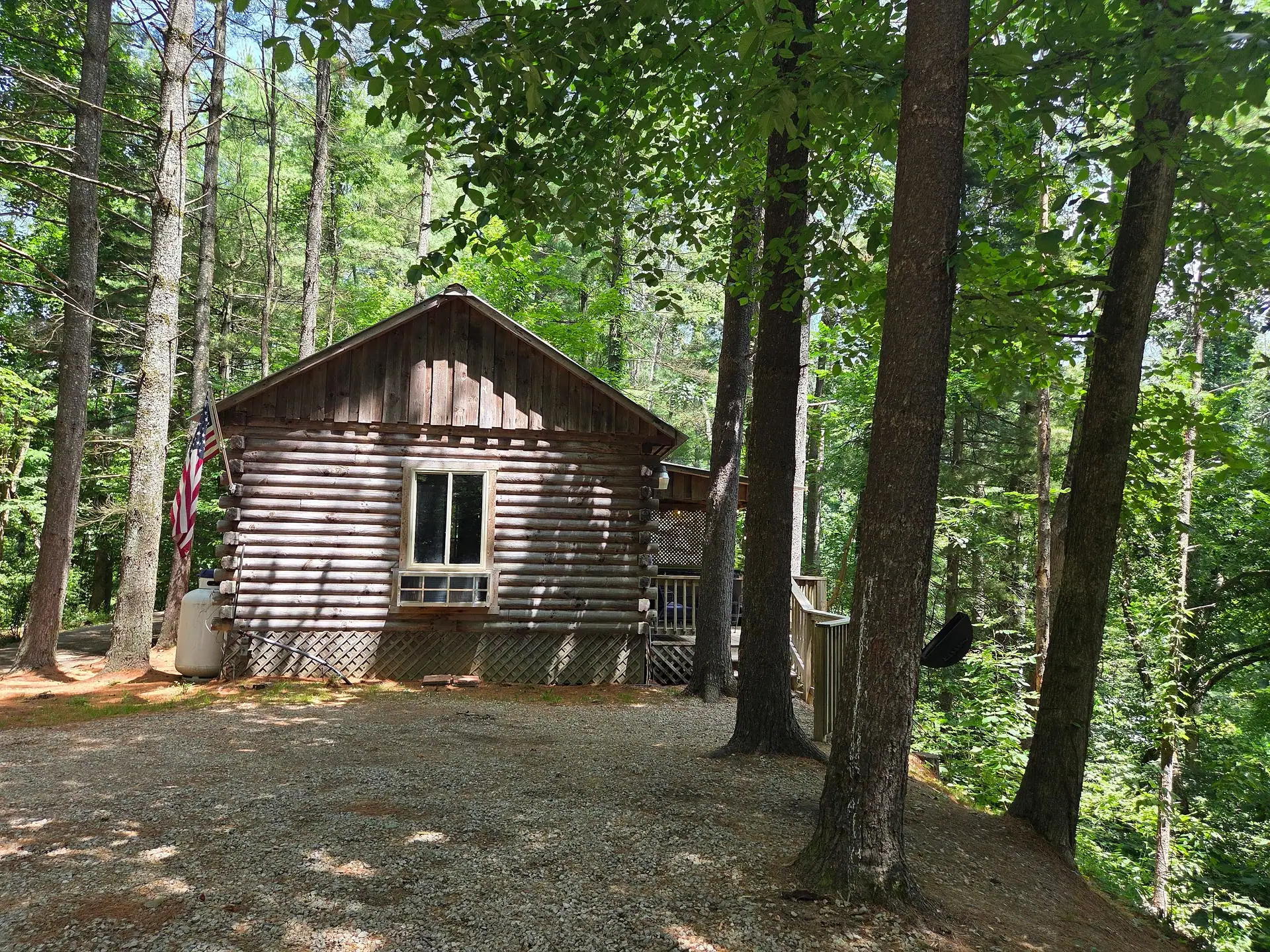 Front view of Eagles Nest log cabin from the gravel drive under tall hardwoods