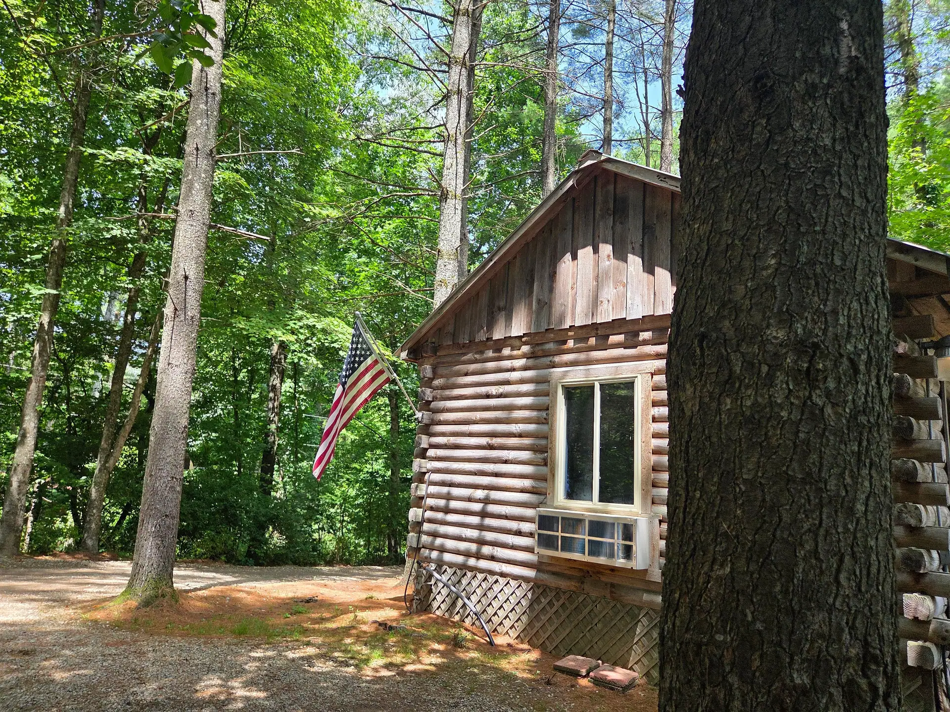 Chinked log gable end of Eagles Nest cabin with an American flag on a sunny day