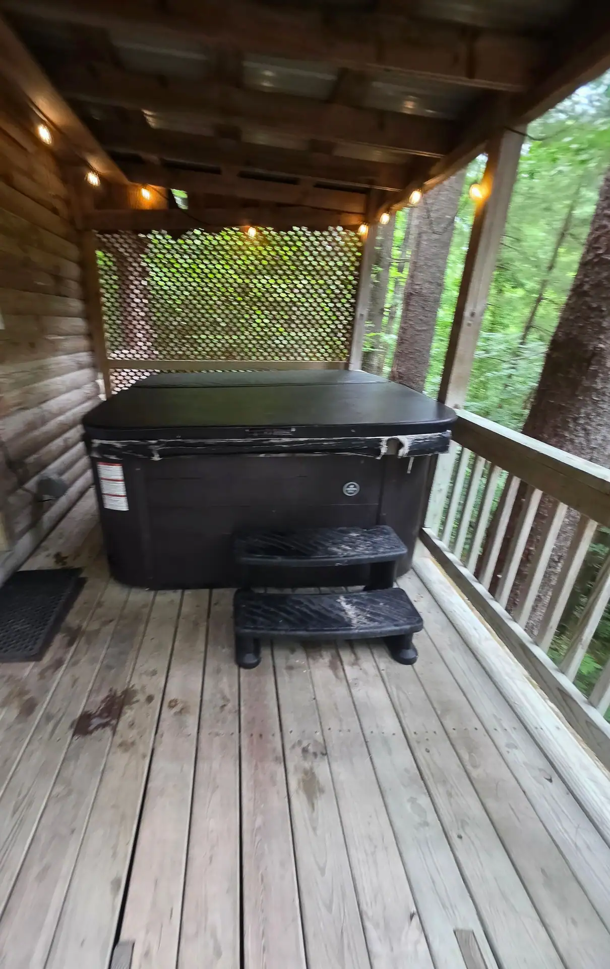 Private hot tub with steps on the covered wooden deck at Eagles Nest cabin