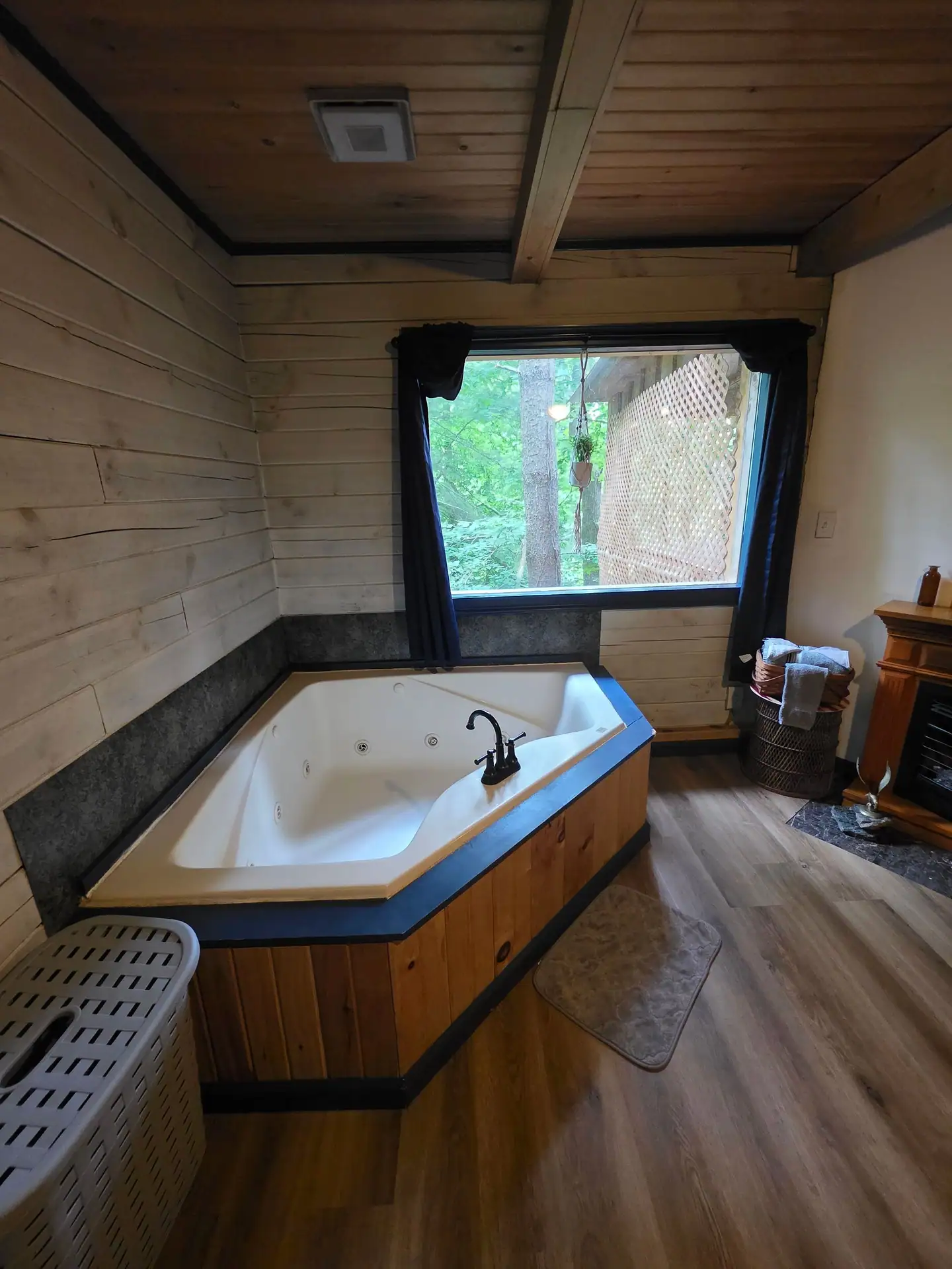 Corner jacuzzi tub below a forest-view window in the Eagles Nest cabin bedroom