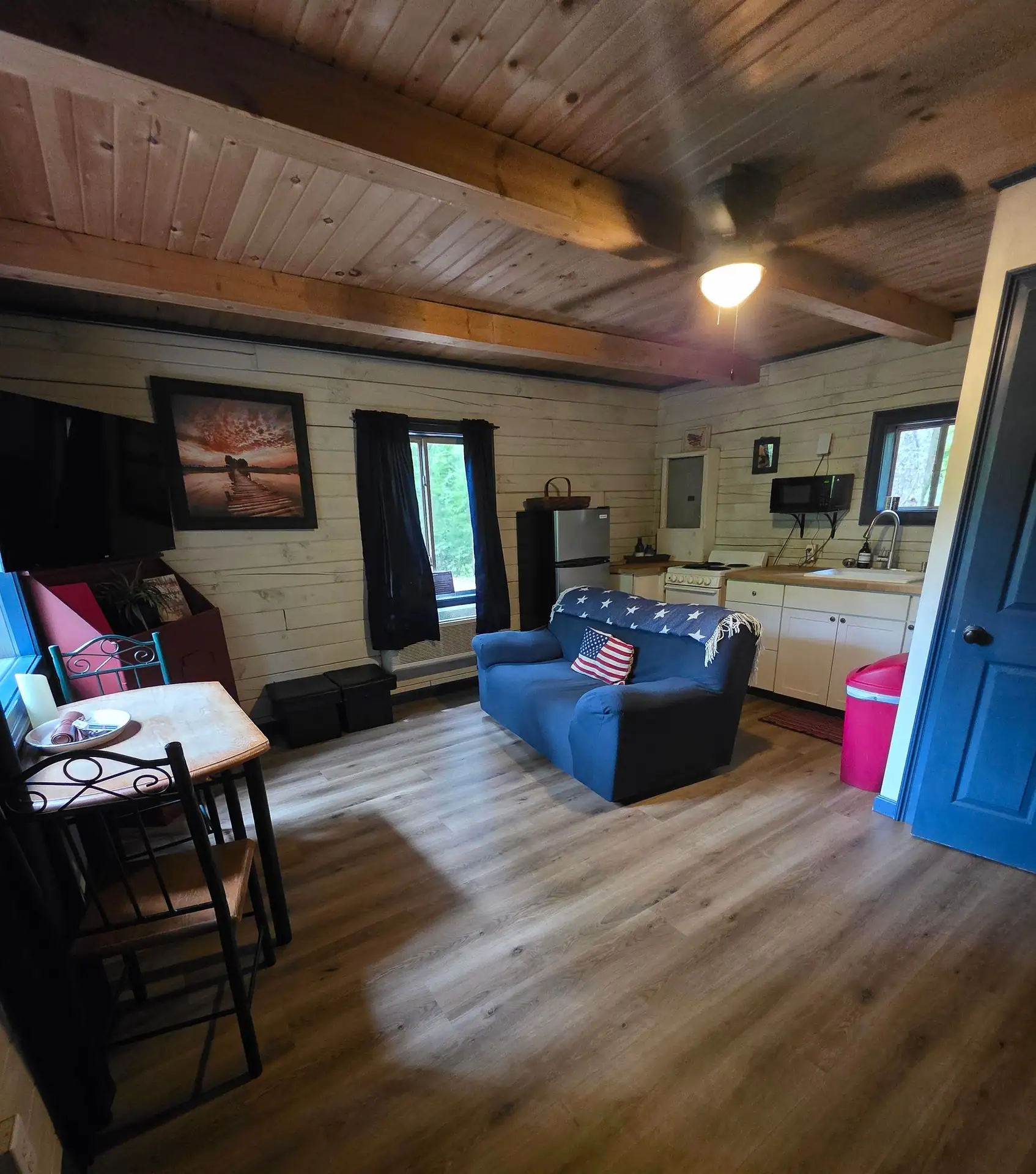 Eagles Nest cabin open living room with wood beam ceiling, blue sofa and kitchen