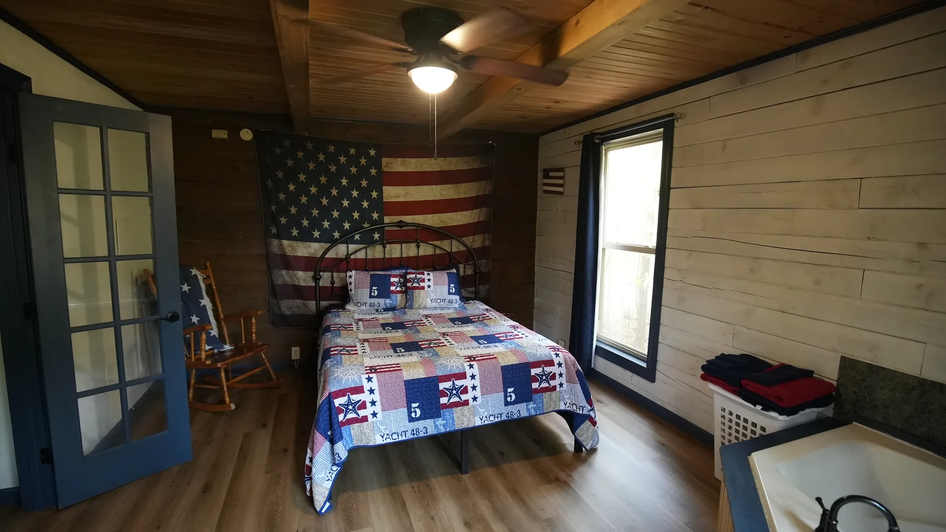 Eagles Nest cabin master bedroom with iron bed frame, patriotic quilt, and American flag wall decor