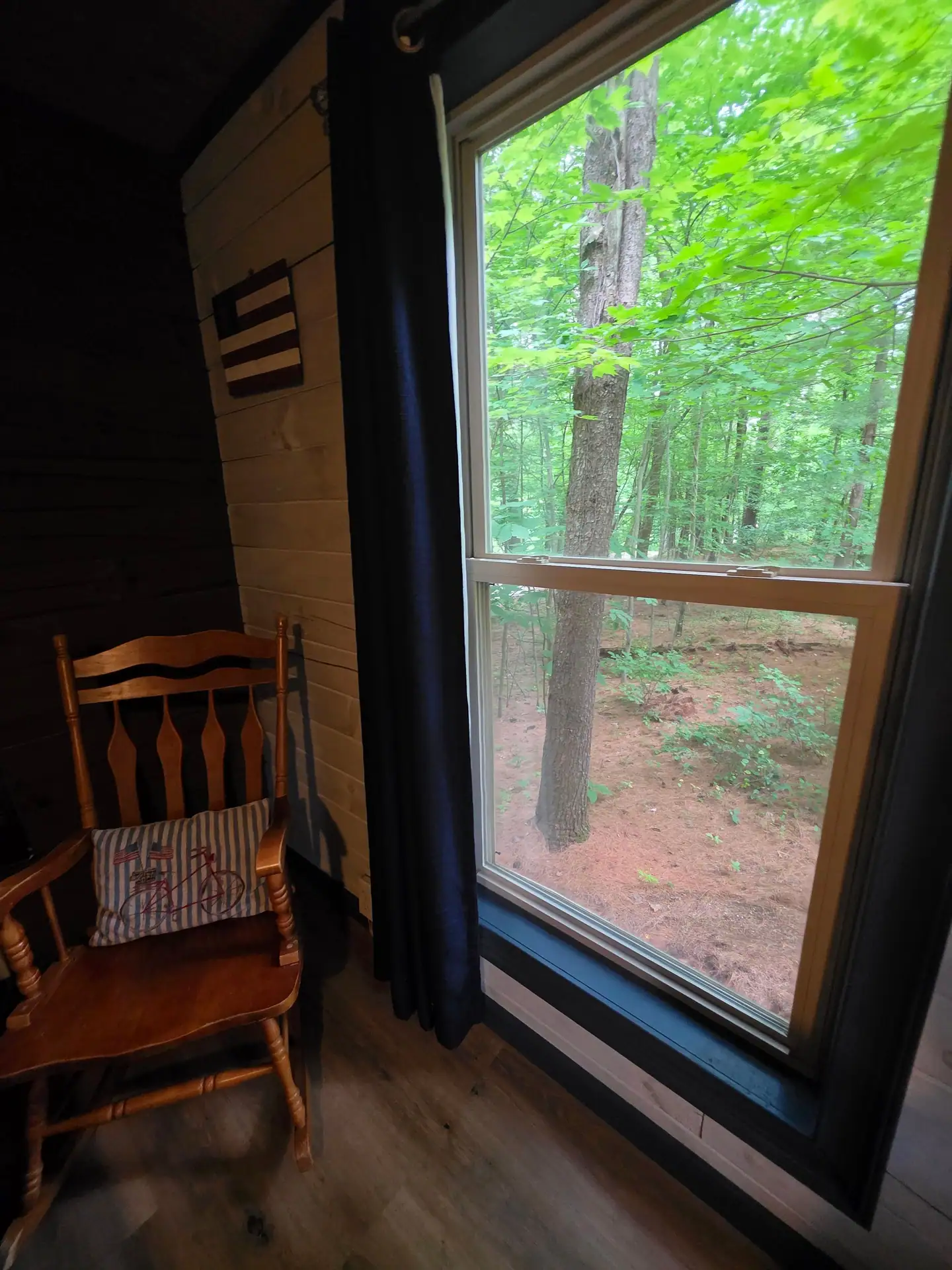 Wooden rocking chair beside a tall bedroom window at Eagles Nest cabin