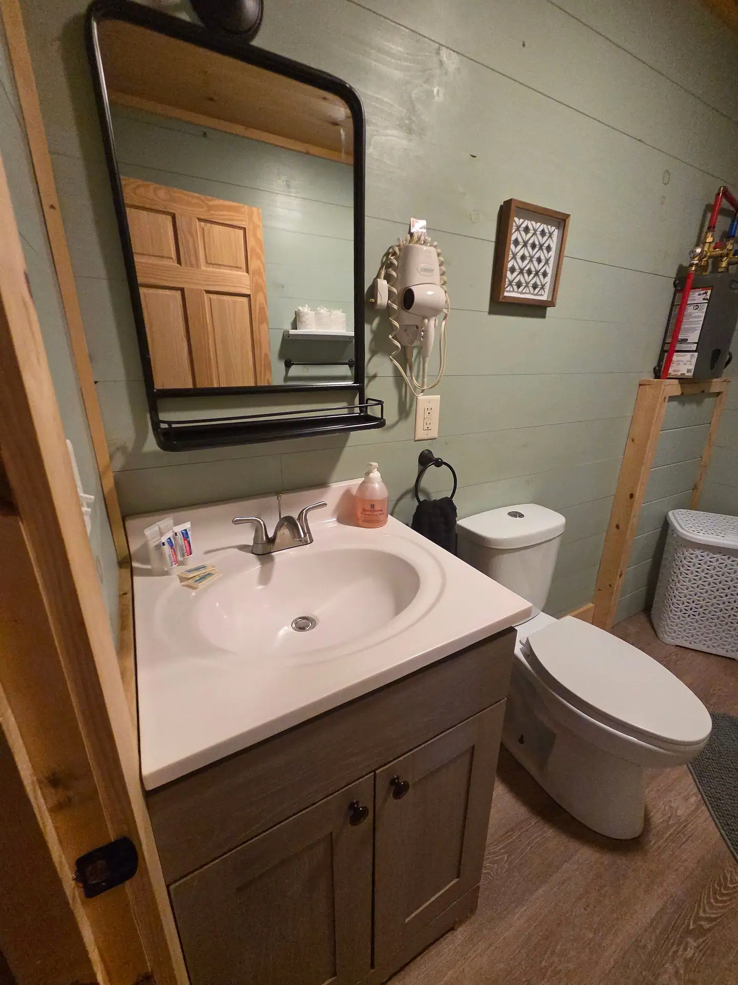 Bathroom vanity with black-framed mirror and wall hair dryer at Firefly's Landing