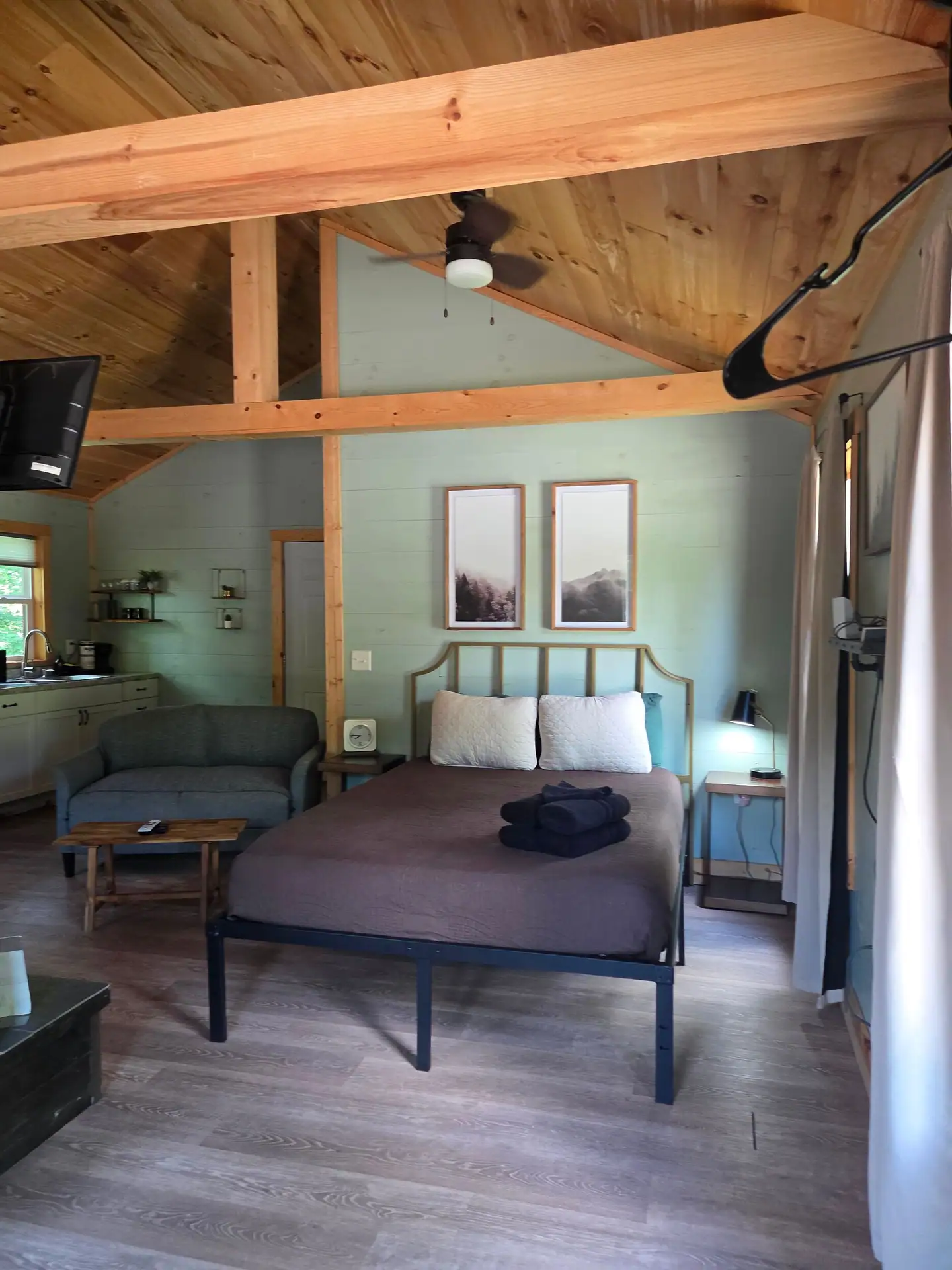 Queen bed with the sofa and kitchenette behind it at Firefly's Landing