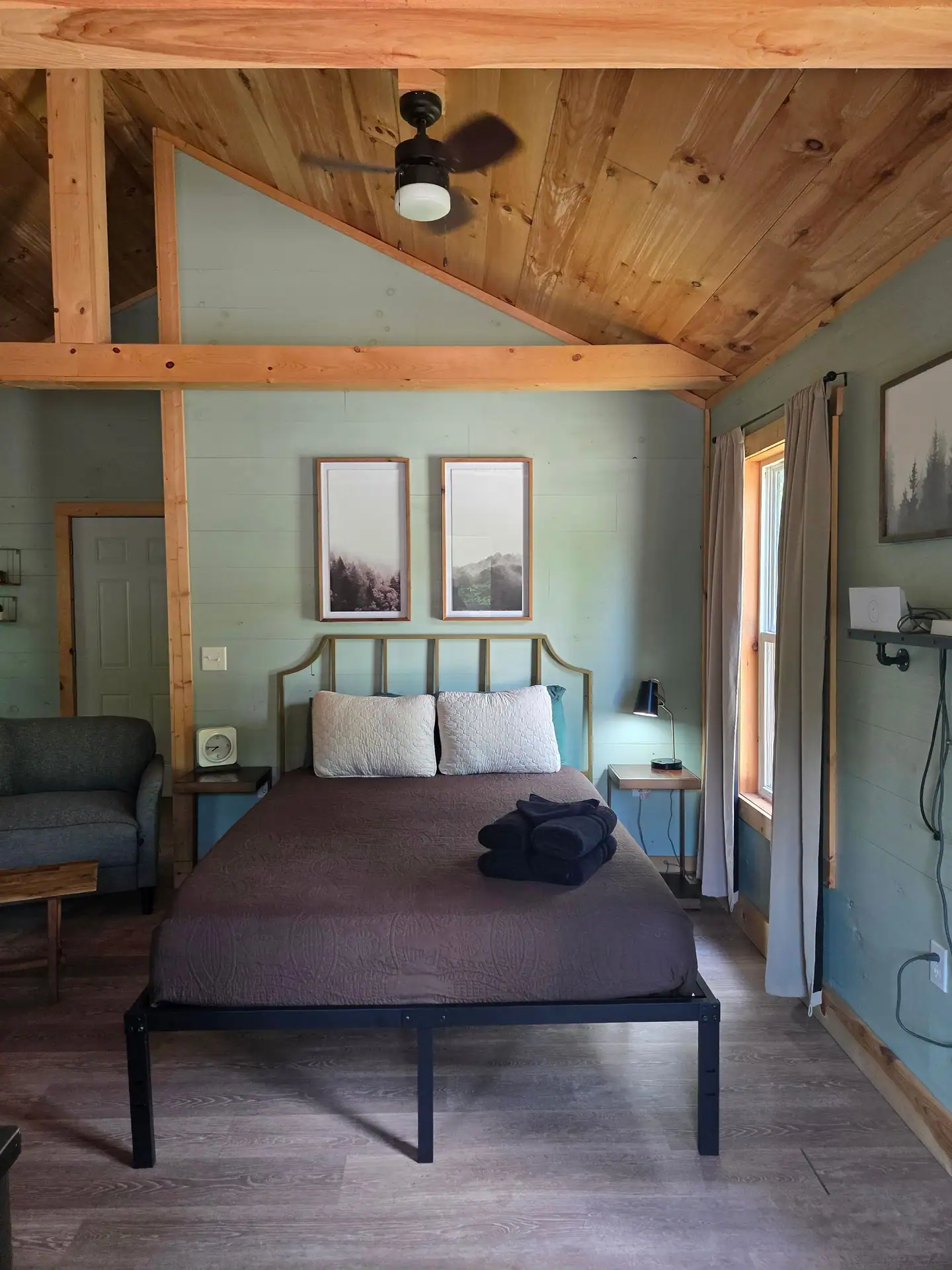 Queen bed with framed forest prints under a vaulted wood ceiling at Firefly's Landing