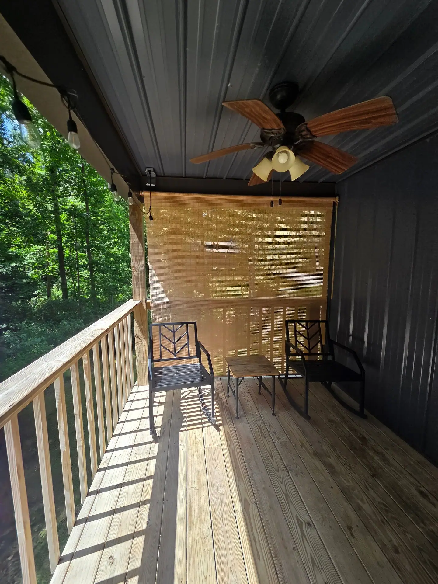 Covered back deck with rocking chairs, bistro table and ceiling fan at Firefly's Landing