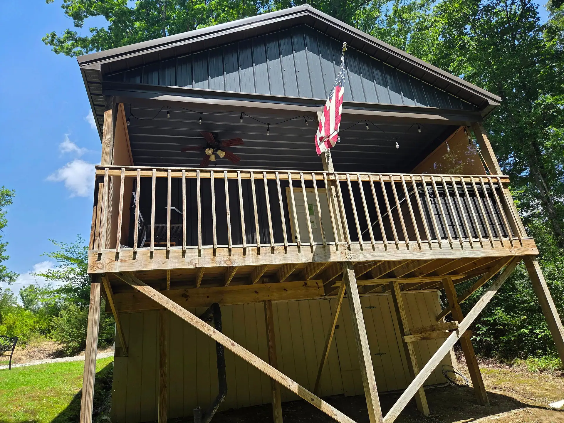 Raised covered back deck with railing and string lights at Firefly's Landing