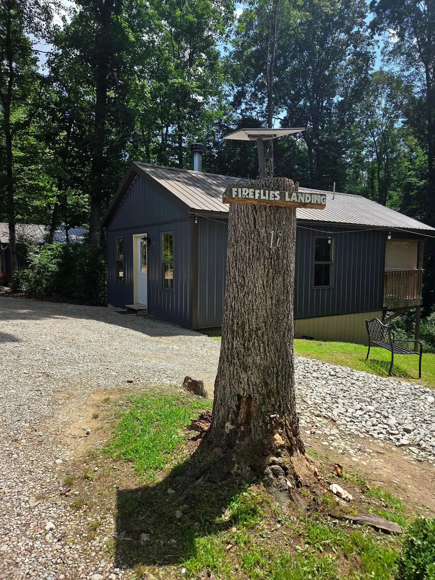 Wooden Firefly's Landing name sign on a tree trunk in front of the cabin