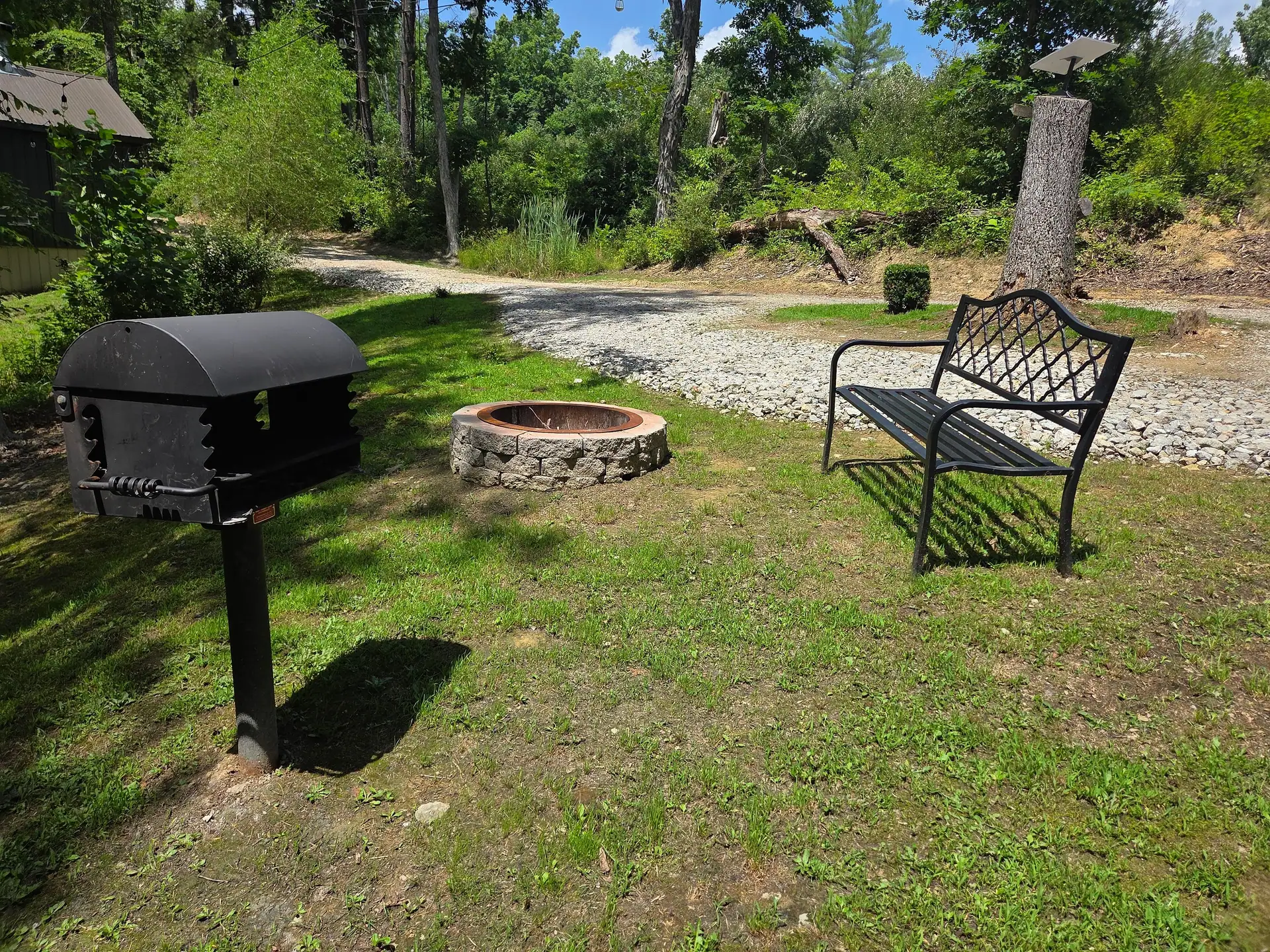 Stone fire pit, garden bench and charcoal grill in the yard at Firefly's Landing