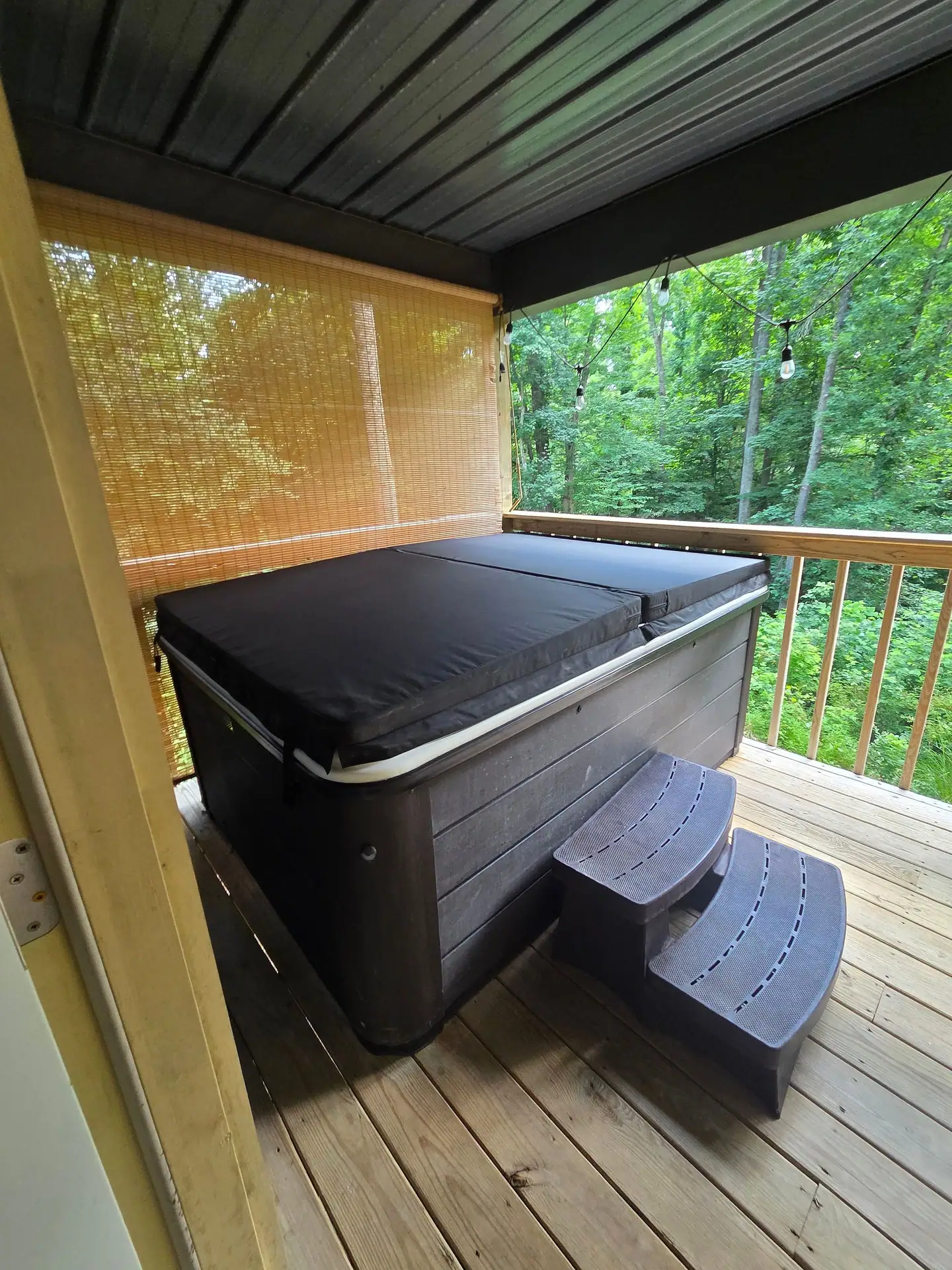 Private hot tub on the covered back deck with forest views at Firefly's Landing